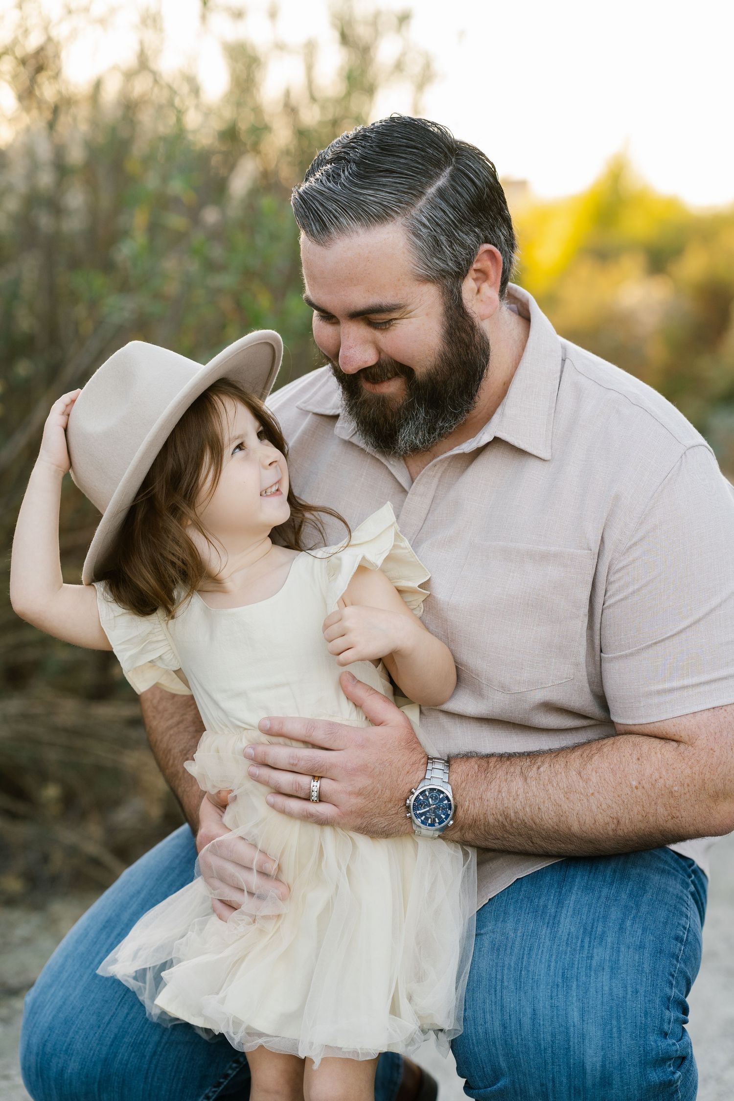 Parent and child share a tender moment while sitting outdoors wearing coordinating neutral outfits.