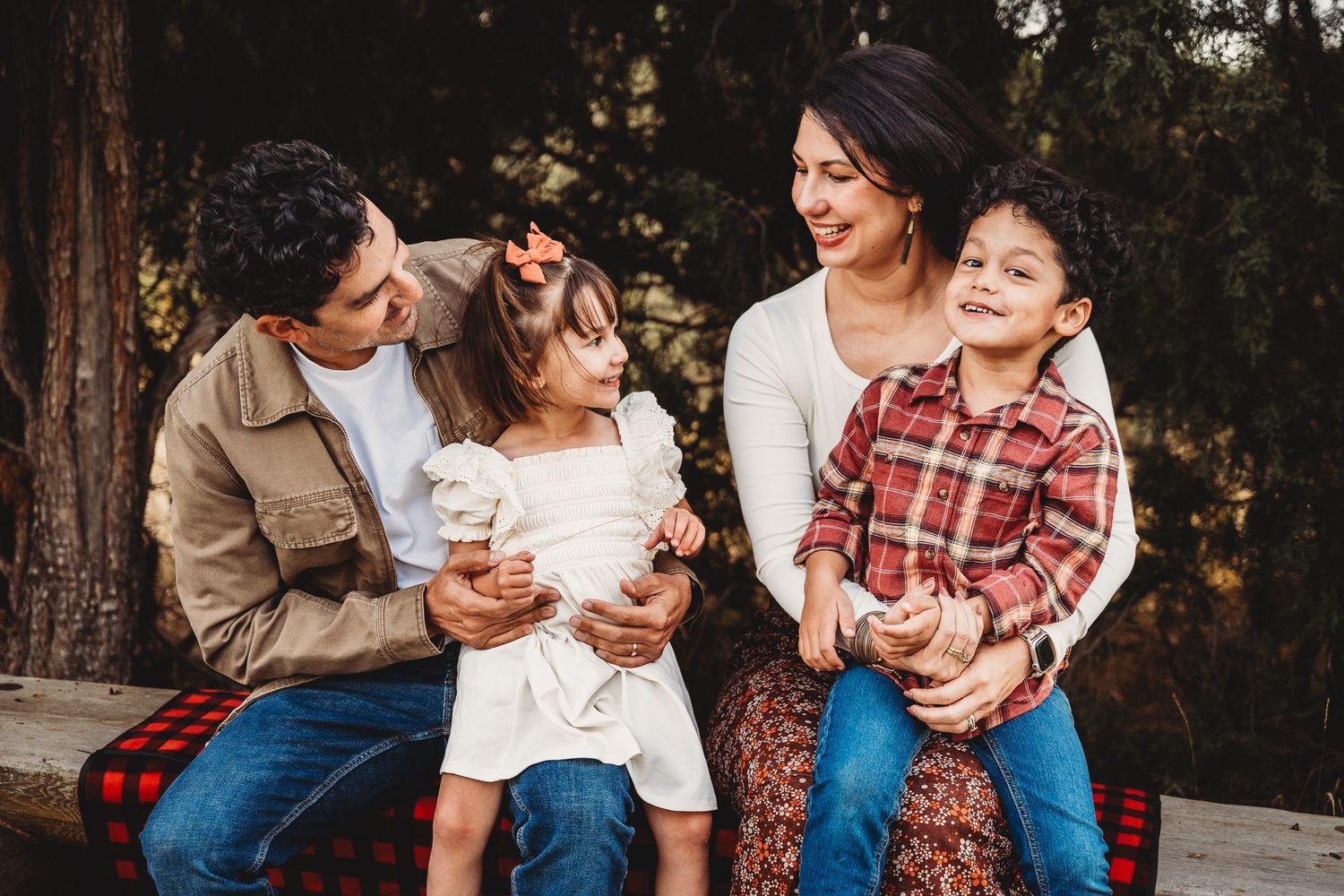 Family sitting together outdoors during a casual photo session in a natural setting.