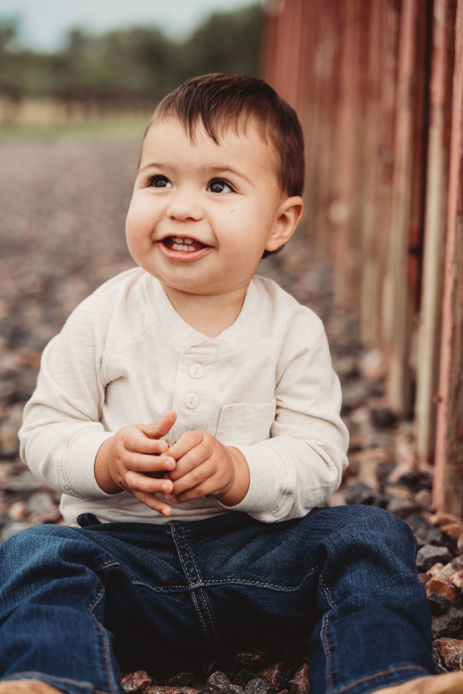 A sequence of four shots showing a baby in white sweater and jeans sitting outdoors with a joyful expression.