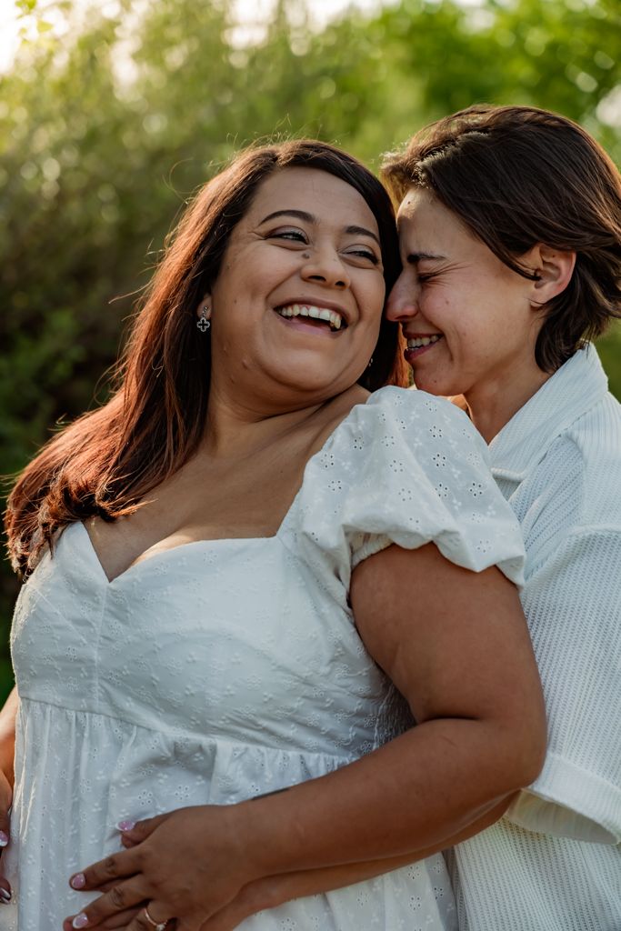 An intimate portrait of two people laughing together in warm evening sunlight.