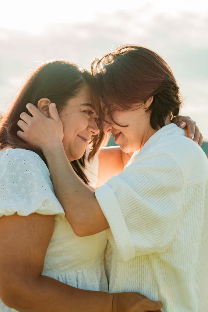 A couple in white sharing an intimate moment at sunset.