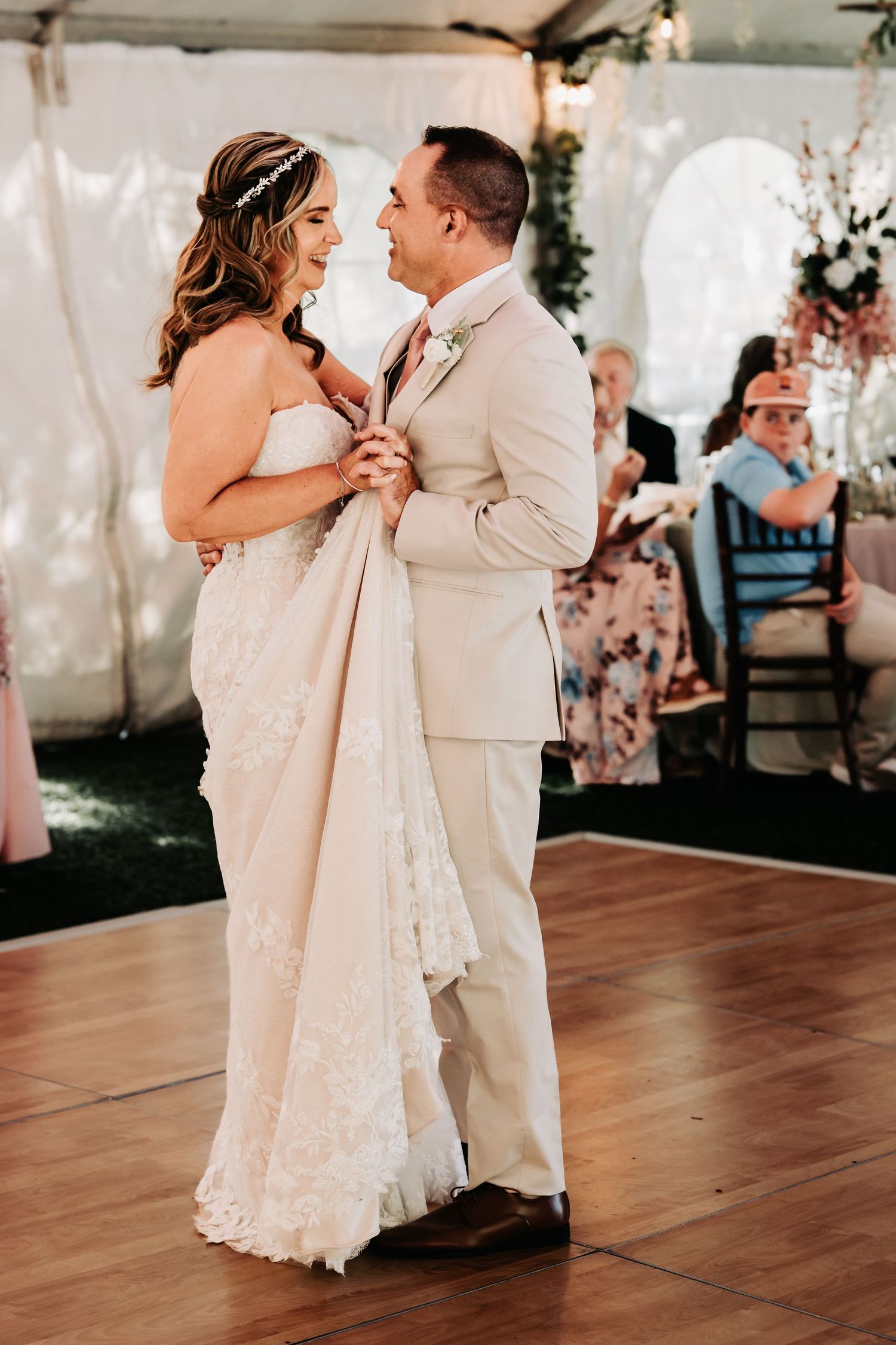 Bride and groom share their first dance under a tent at their elegant outdoor wedding reception.