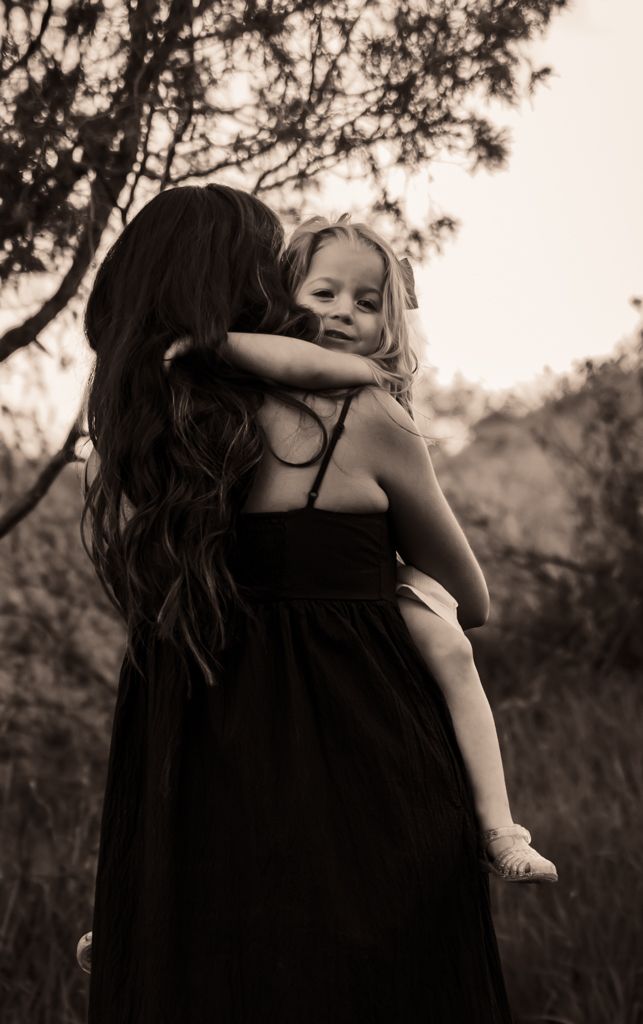 Black and white photo of intimate embrace against natural outdoor background.