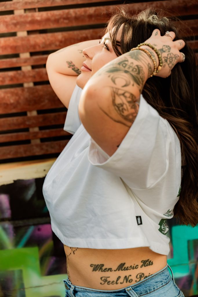 Close-up of tattooed Woman in white crop top showing body art.