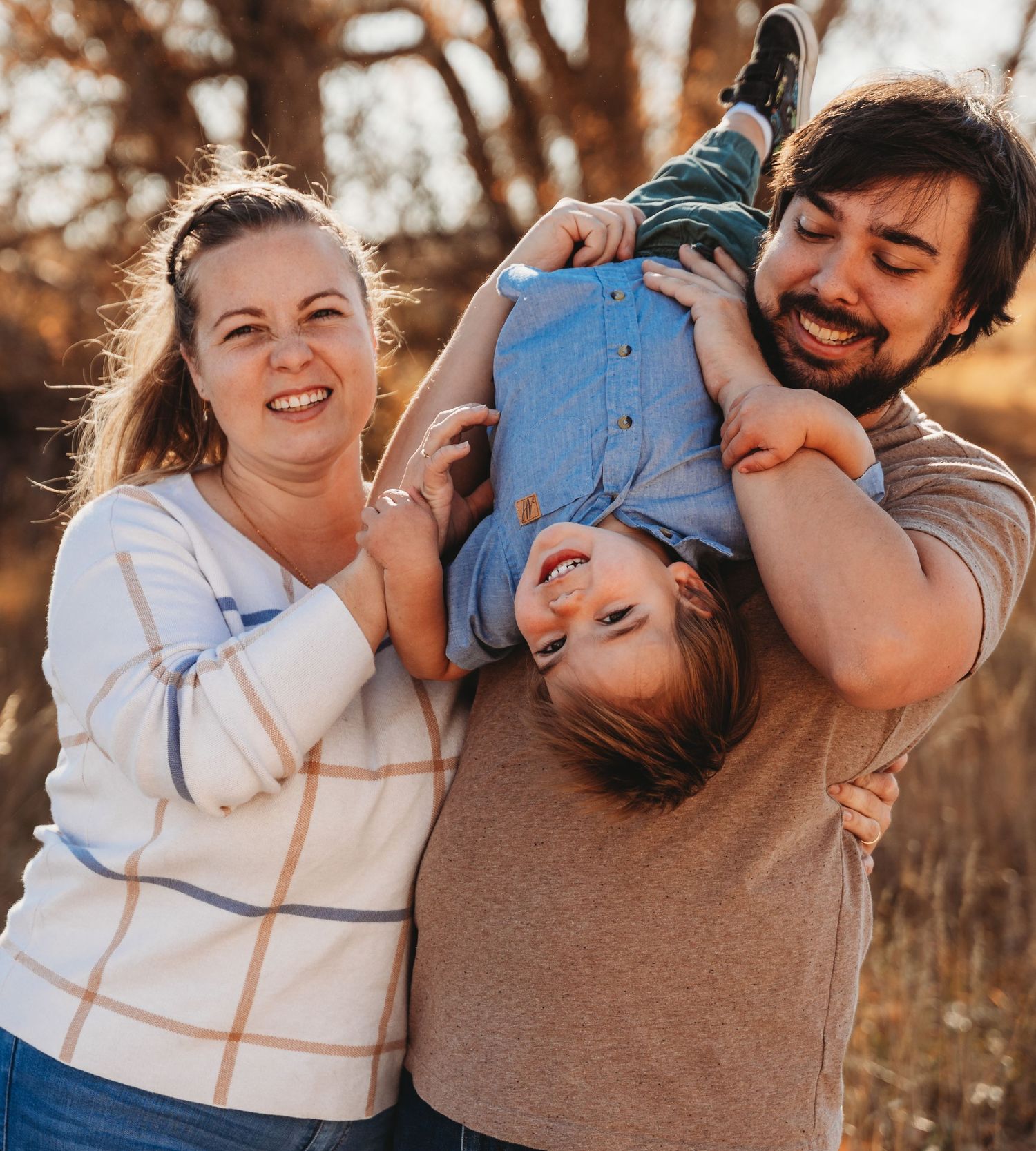 Couple embraces and laughs together during outdoor autumn photoshoot at sunset.
