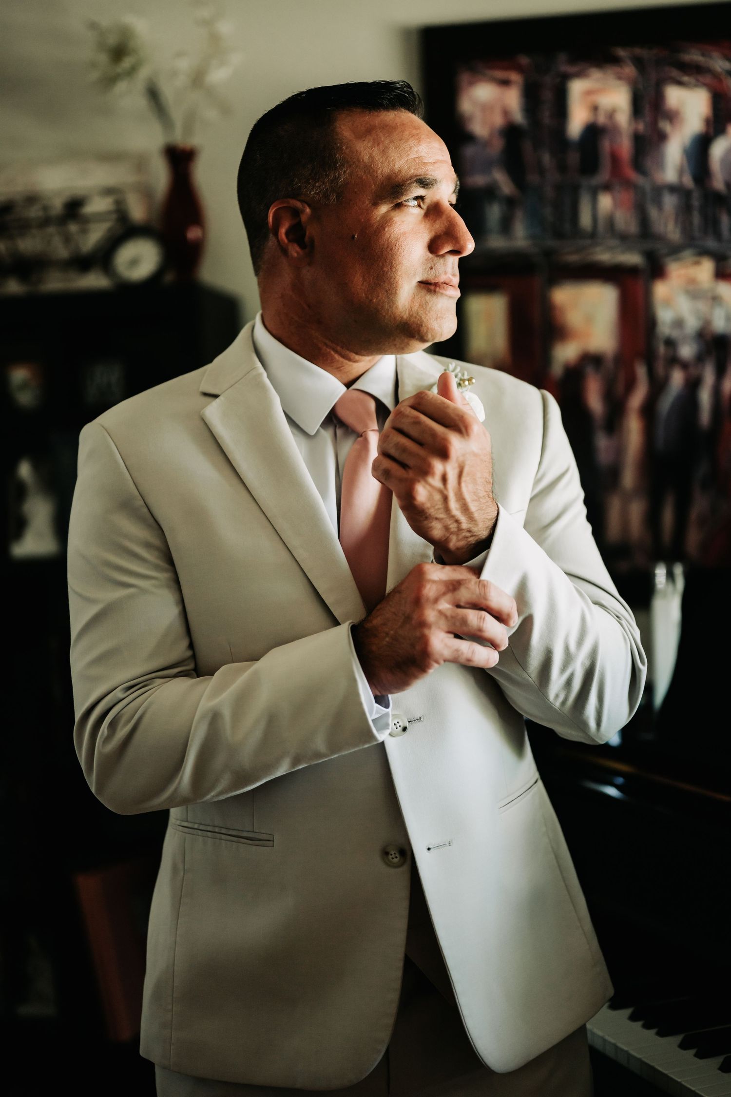 Groom in a light beige suit adjusting his cufflinks before the wedding ceremony.