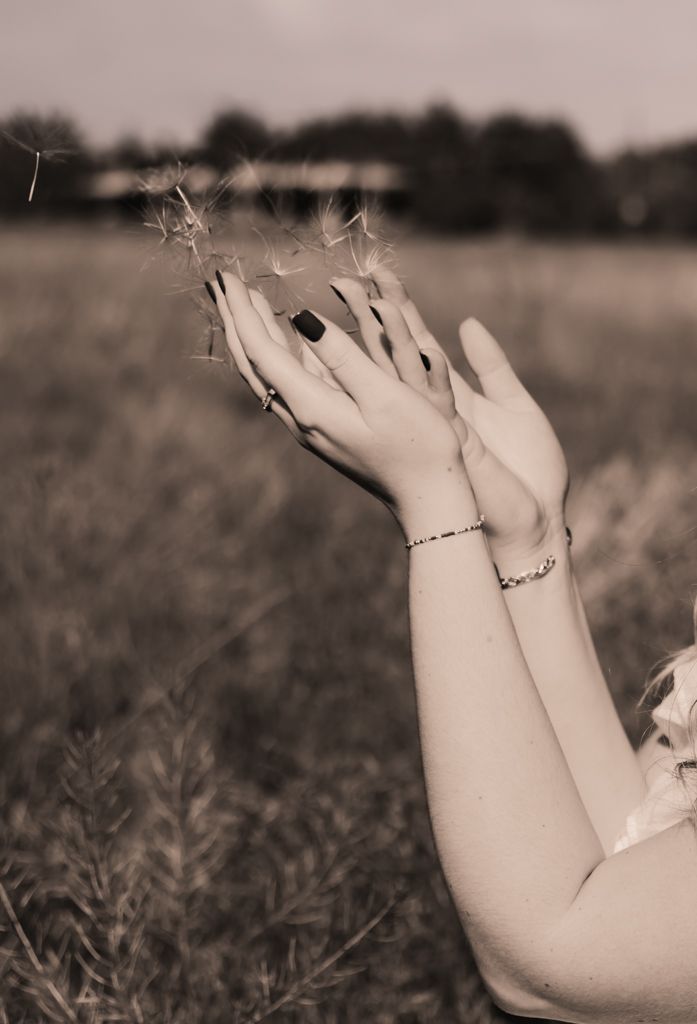 Artistic black and white photo of hands raised gracefully against a blurred background.