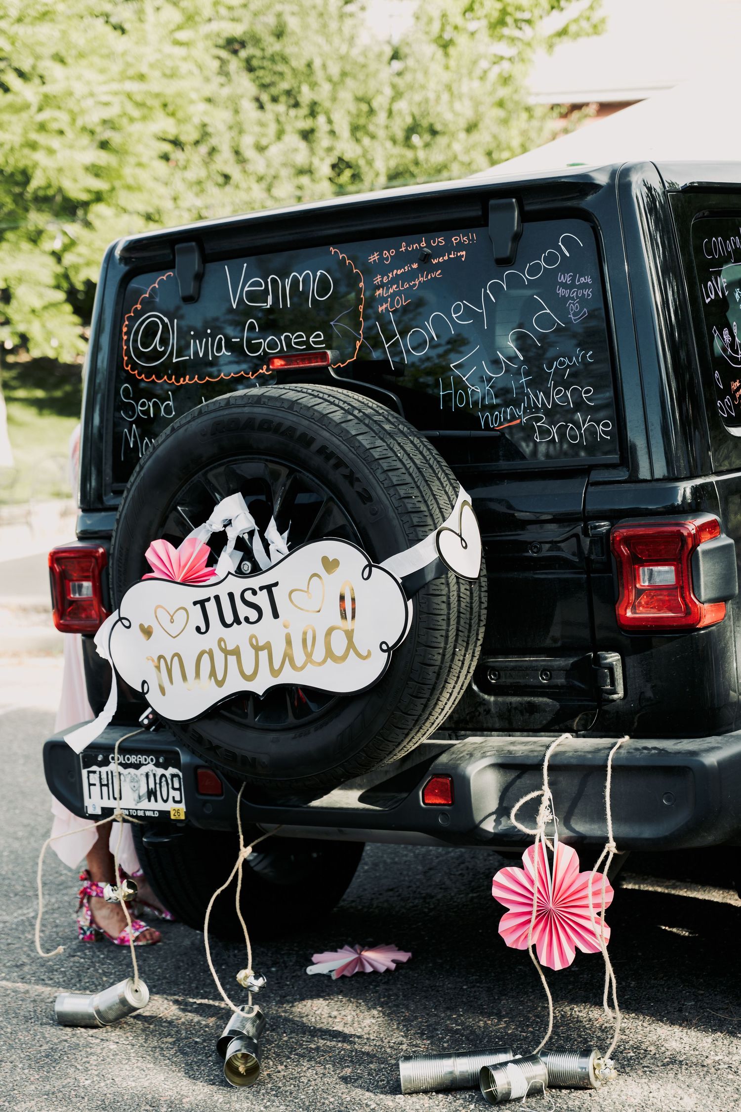 Black Jeep decorated with Just Married sign on spare tire and Venmo honeymoon fund chalk writing on rear window.