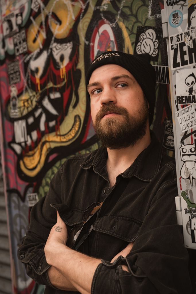 Assistant photographer Jon posing for an urban portrait against a colorful graffiti wall in the RiNo Art District, Denver.