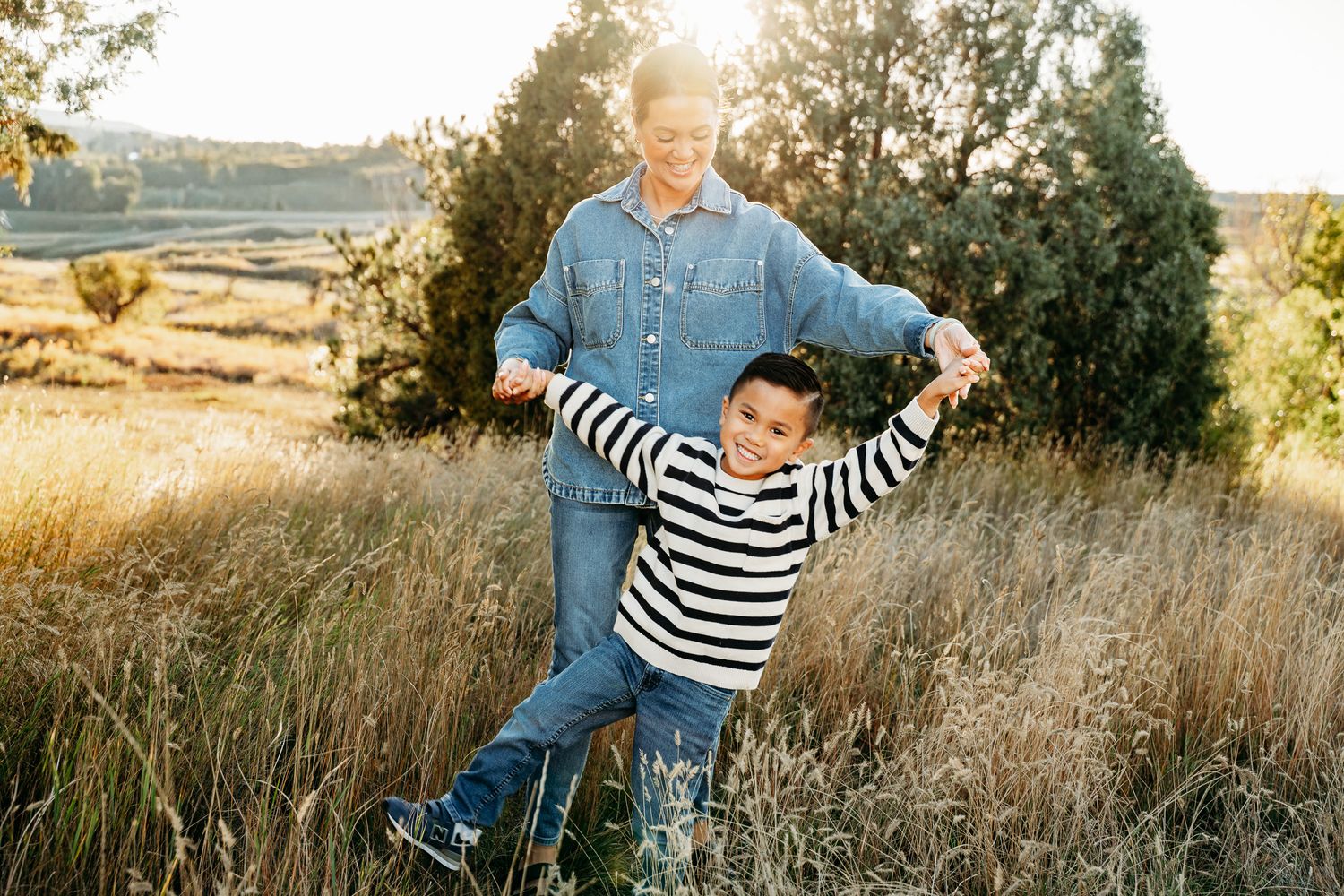 Candid outdoor family photoshoot in a golden field during sunset with natural lighting and casual attire.