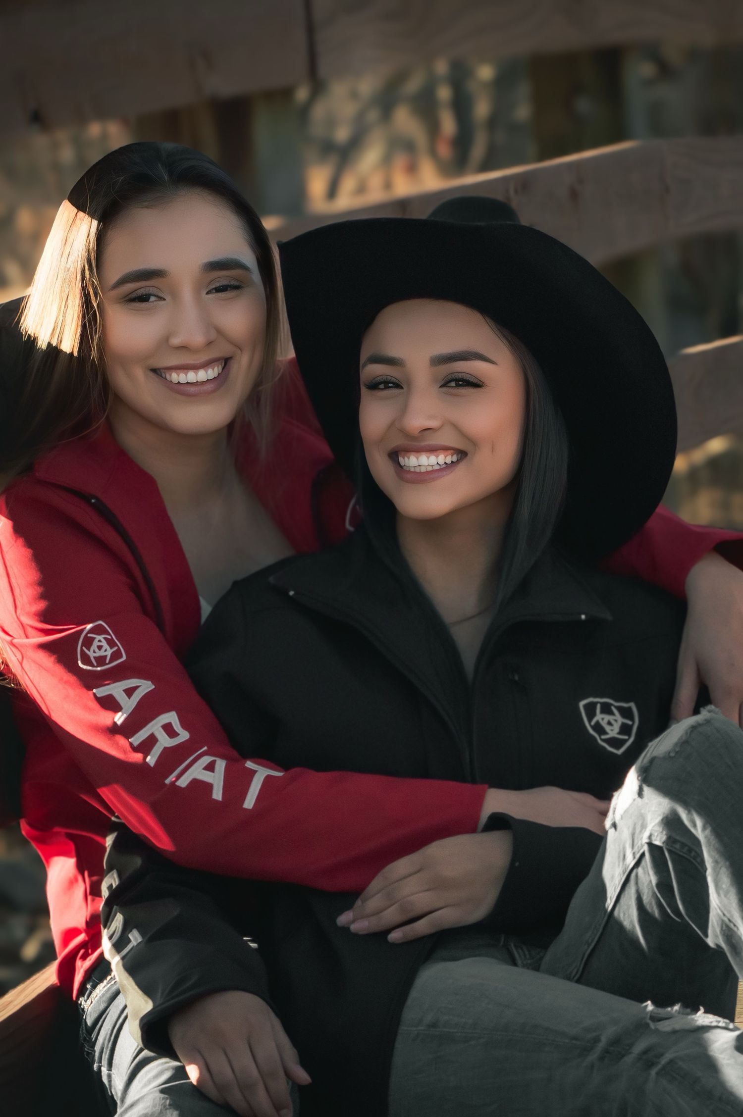 couple laugh together while wearing hooded sweatshirts outdoors.