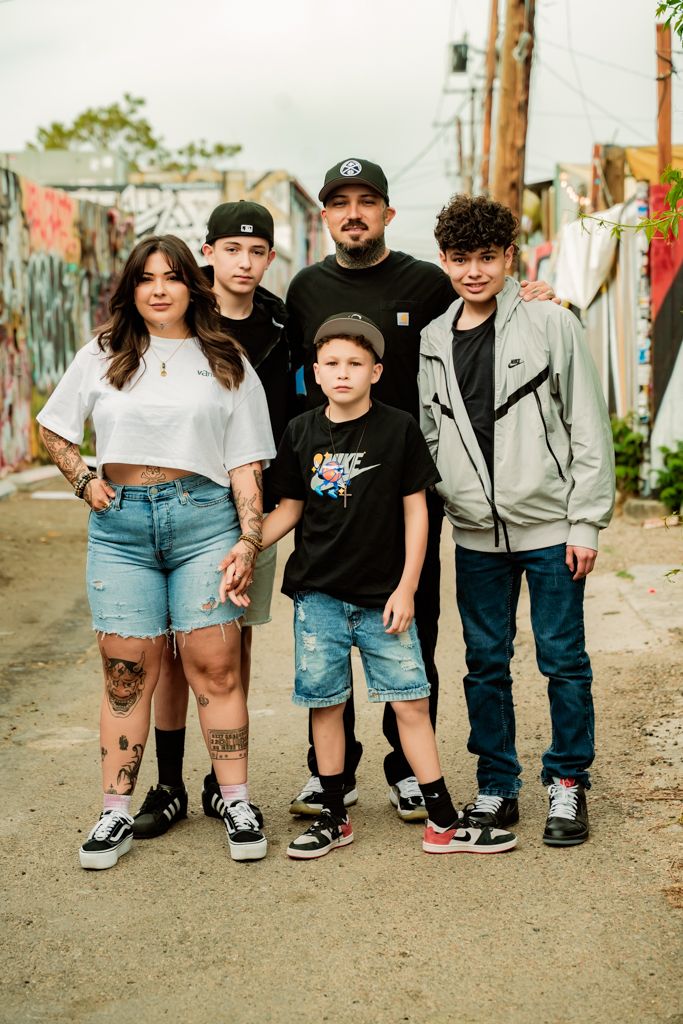 Group photo of five people in casual streetwear against colorful graffiti wall.