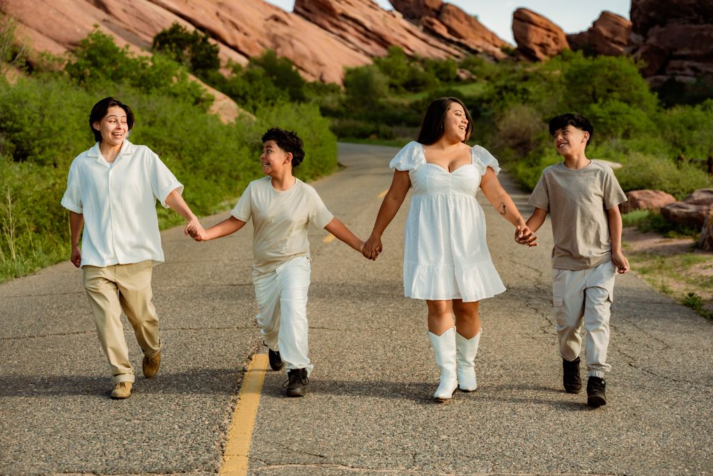 Family walking hand in hand on a road with red rock formations in background.