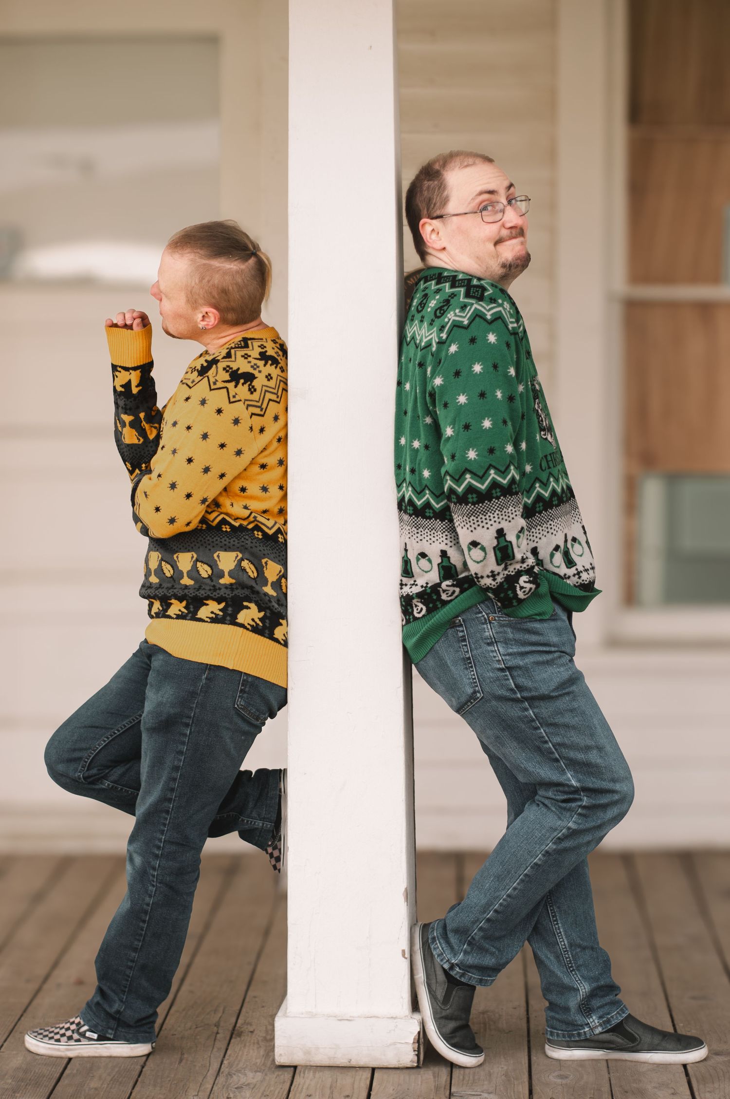Playful poses showing two people in Harry Potter themed holiday sweaters by white columns.