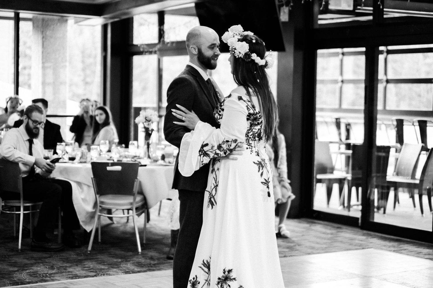 Black and white photo of a bride and groom sharing their first dance at a wedding reception.