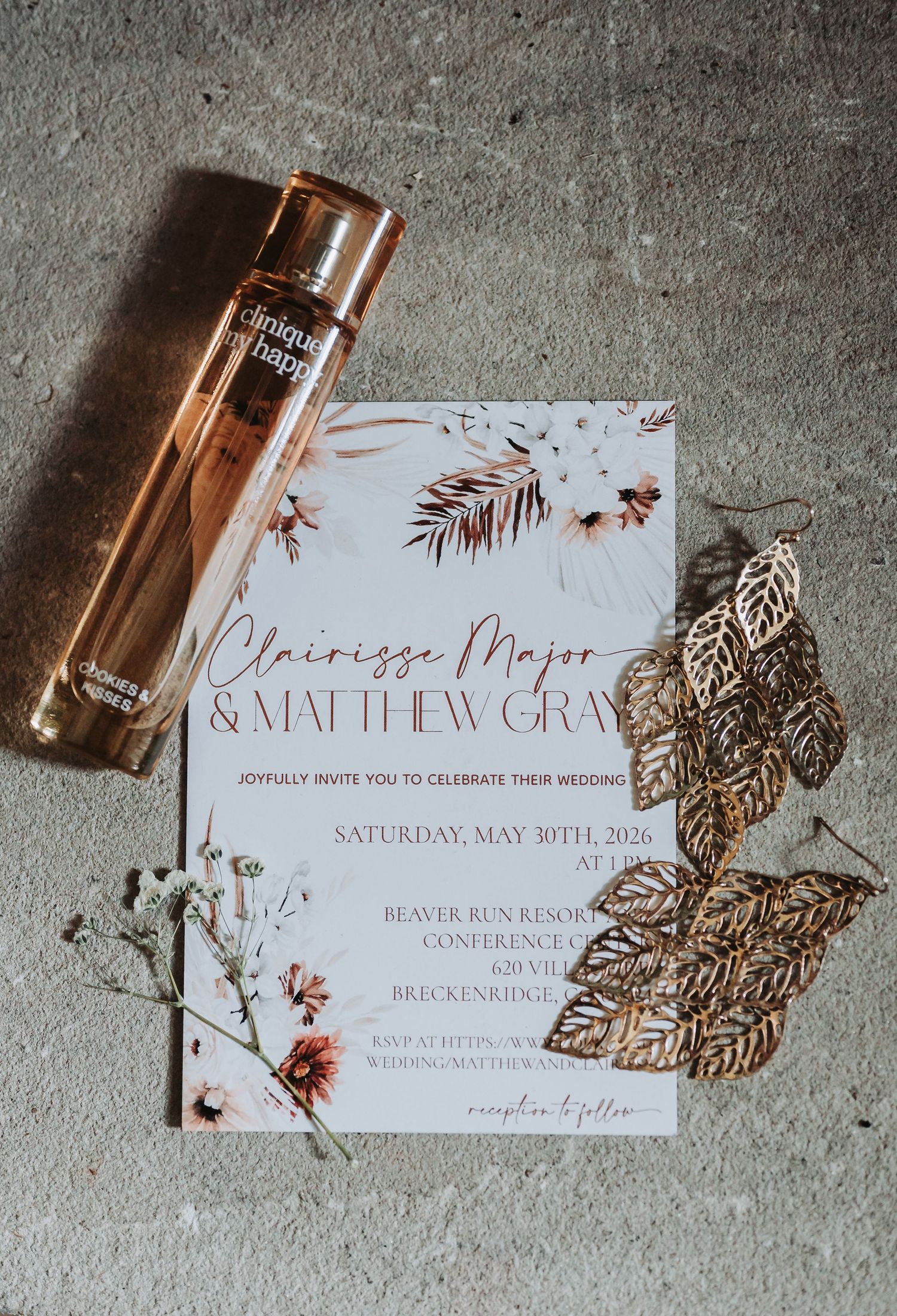 Elegant wedding invitation for Clairissa Major and Matthew Gray on May 30th, 2026, styled with rose gold perfume and gold leaves.