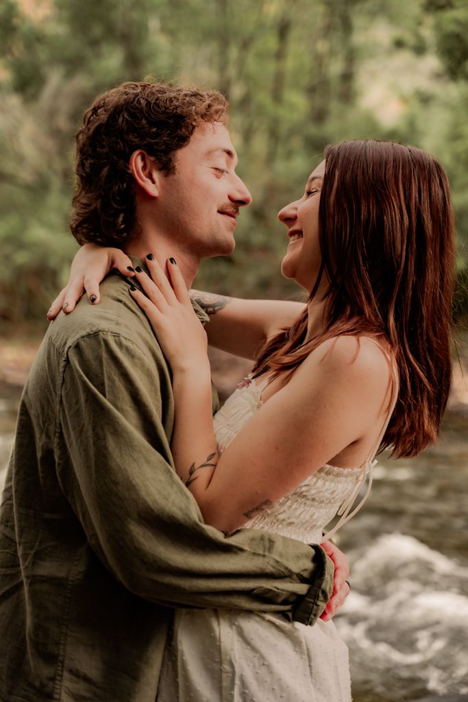Intimate couple portraits against flowing water backdrop in natural lighting.