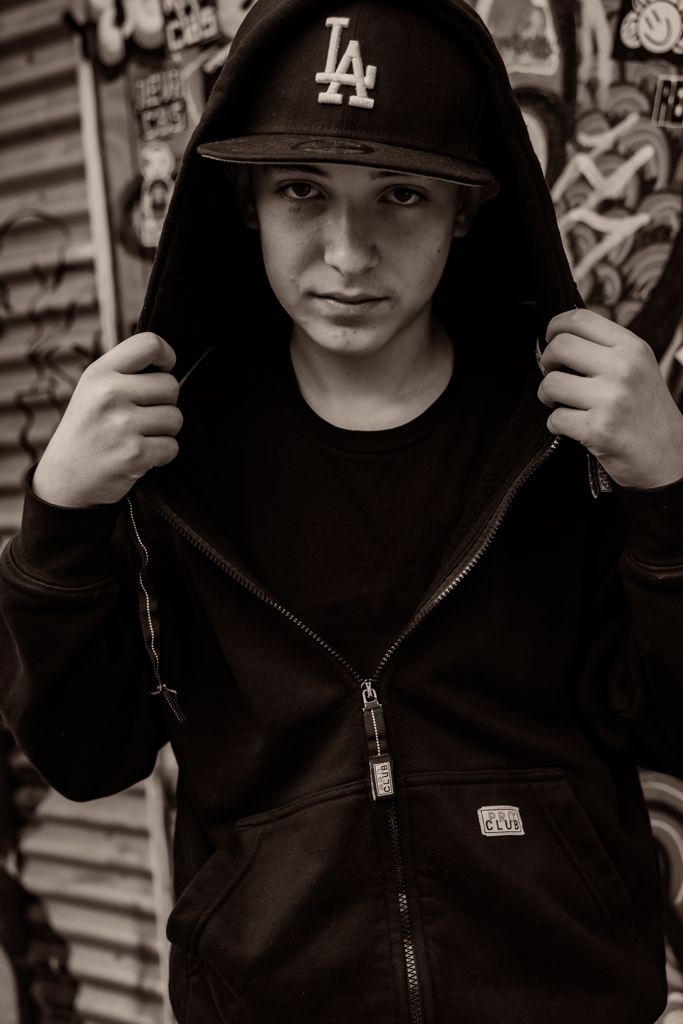 Dramatic black and white portrait series featuring hooded jacket and LA baseball cap.