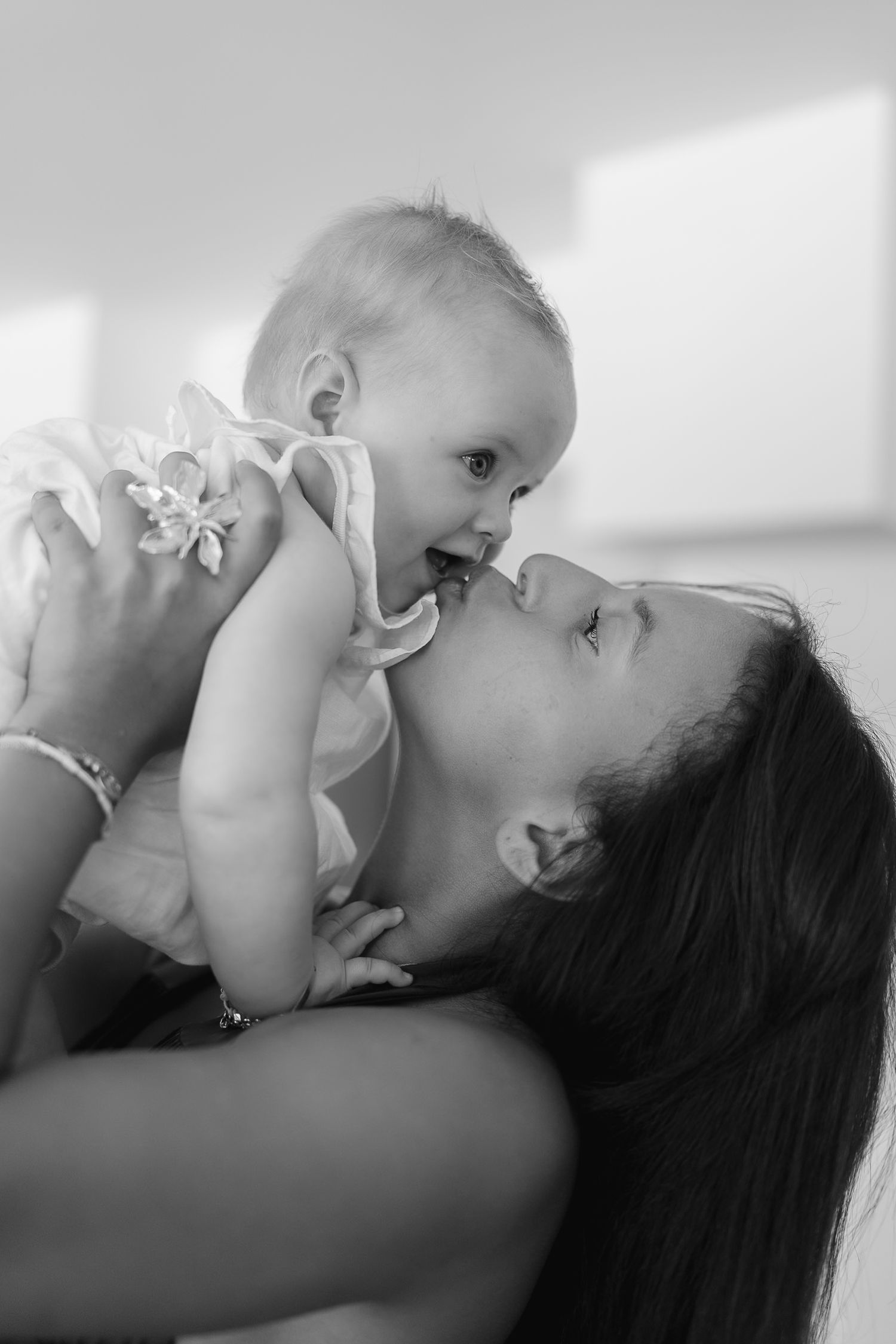 A tender black and white portrait showing a loving embrace between parent and infant.