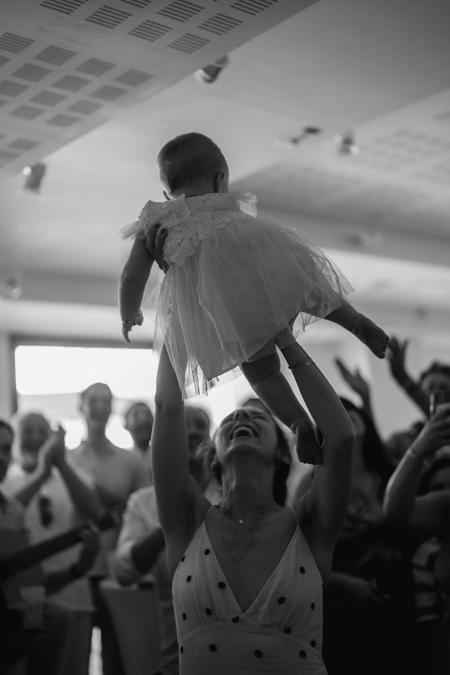 Black and white photo of a lively crowd dancing and celebrating at an indoor event.