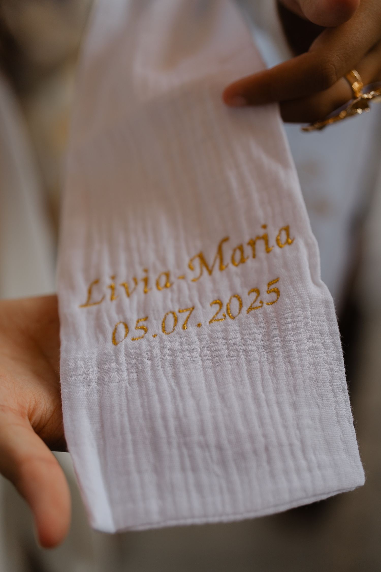 White linen napkins with gold embroidered text showing a wedding date of 05.01.2025.