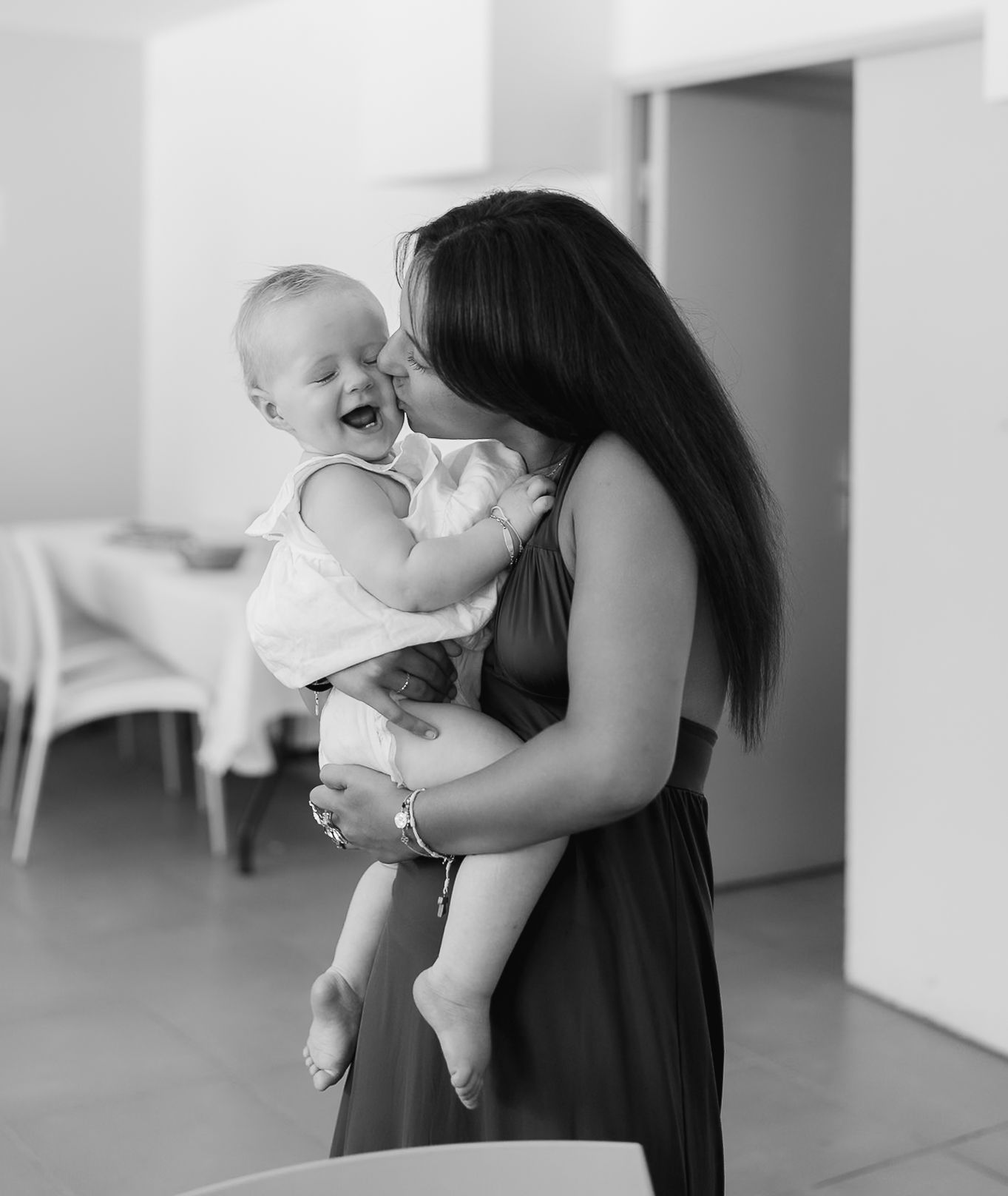 Monochromatic image showing tender moments between caregiver and infant in a minimalist setting.