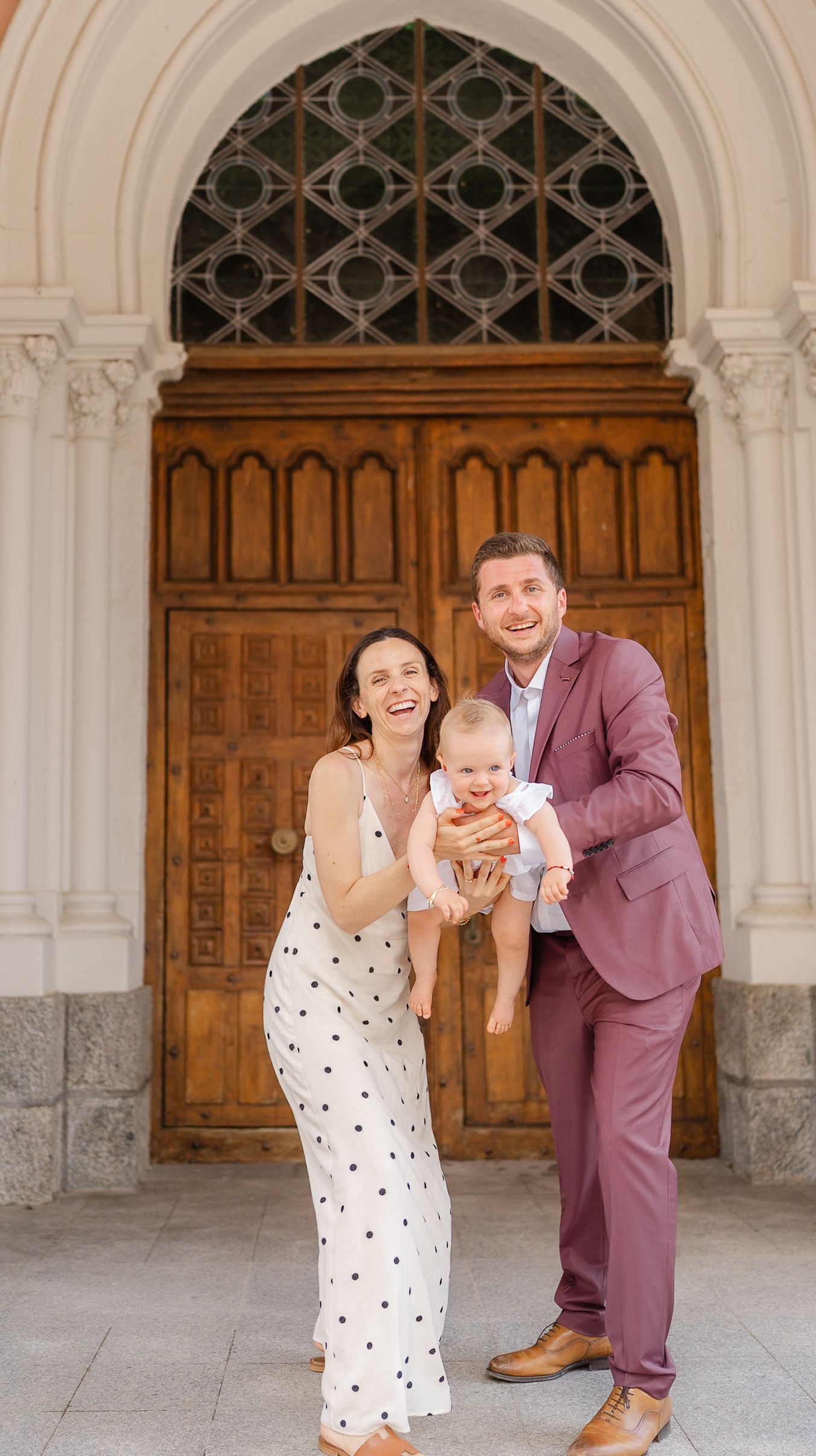 A family poses together in front of ornate wooden church doors during a special celebration.