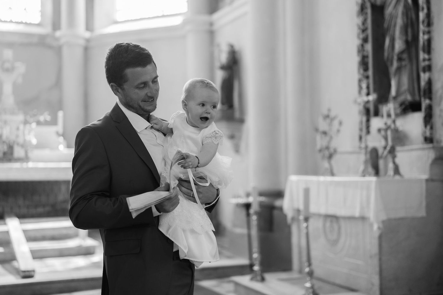 Black and white photo of a baby being held in a bright modern interior space.