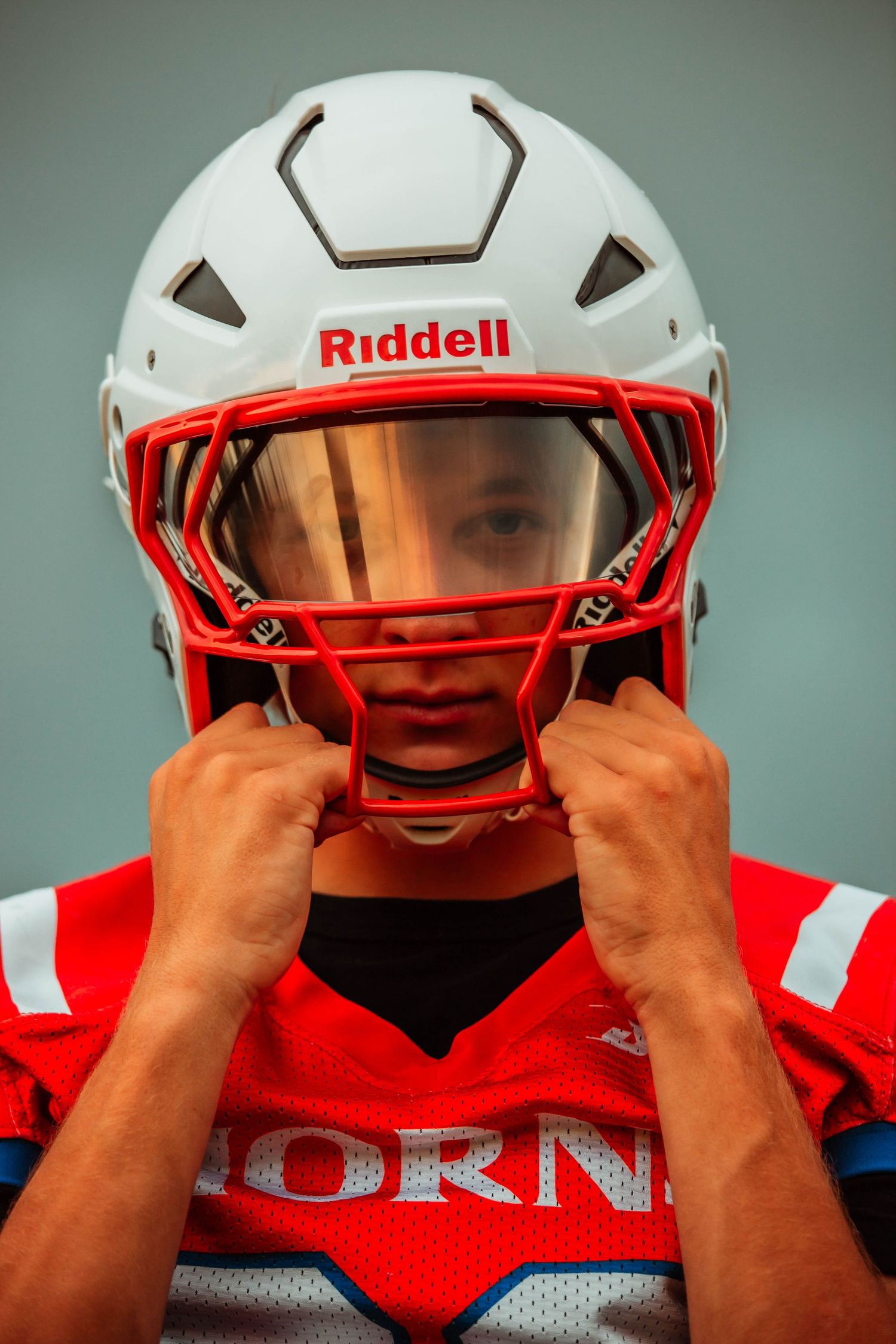 Close-up sequence showing hands adjusting white football helmet with red face mask.