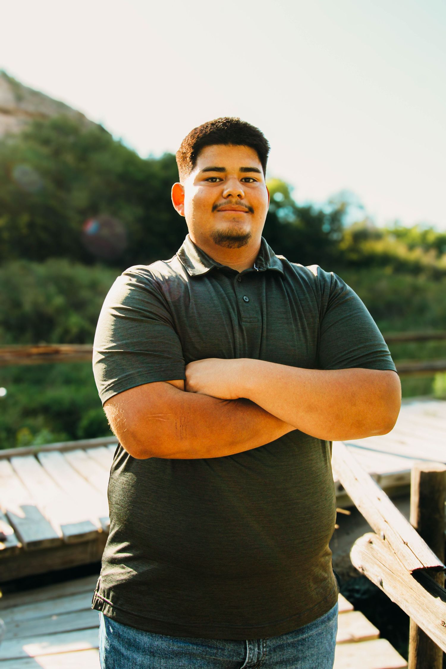 A person in a black shirt poses confidently outdoors with arms crossed in a series of connected portrait shots.