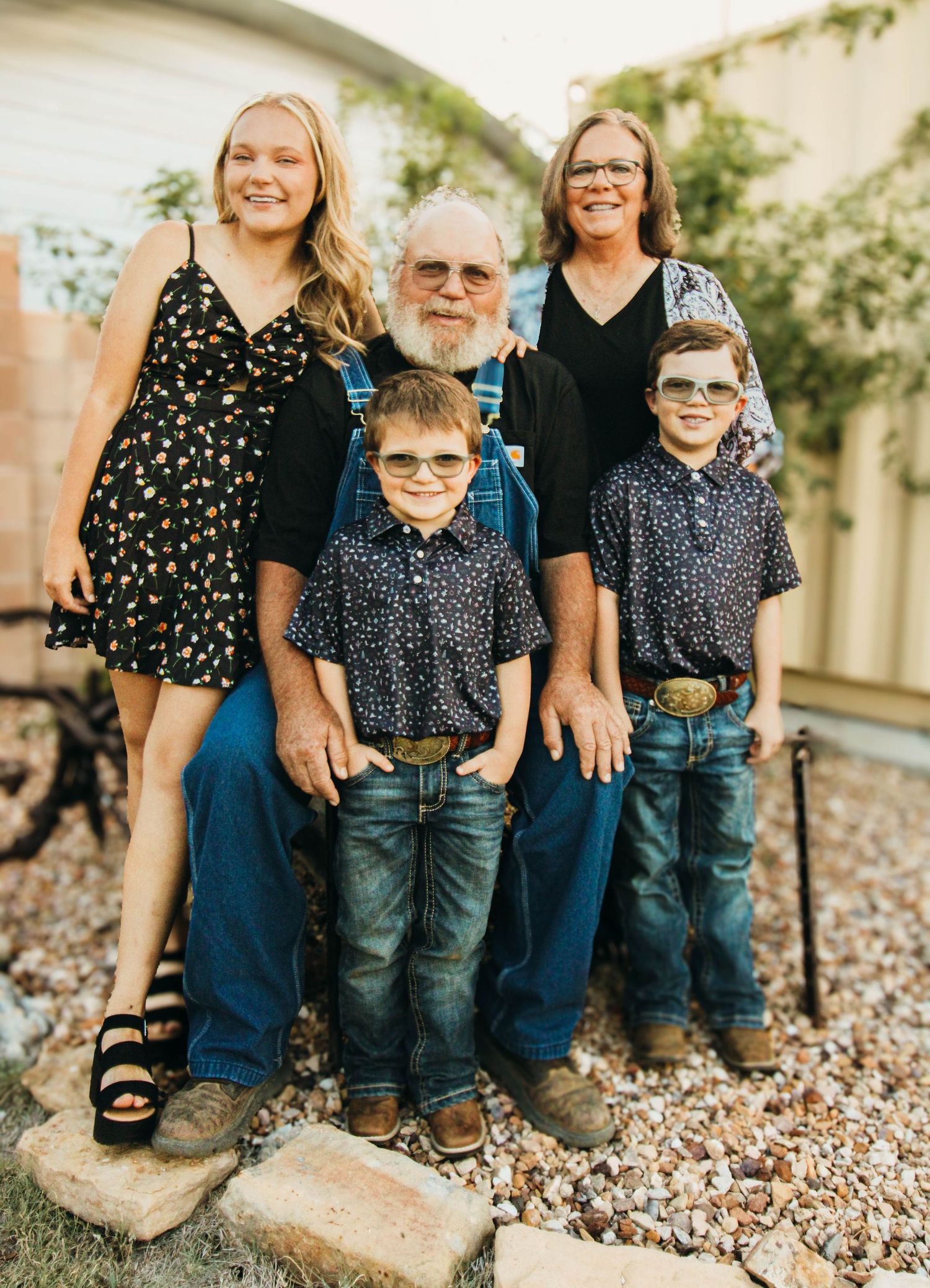 A multigenerational family group poses together on stone steps in casual attire.