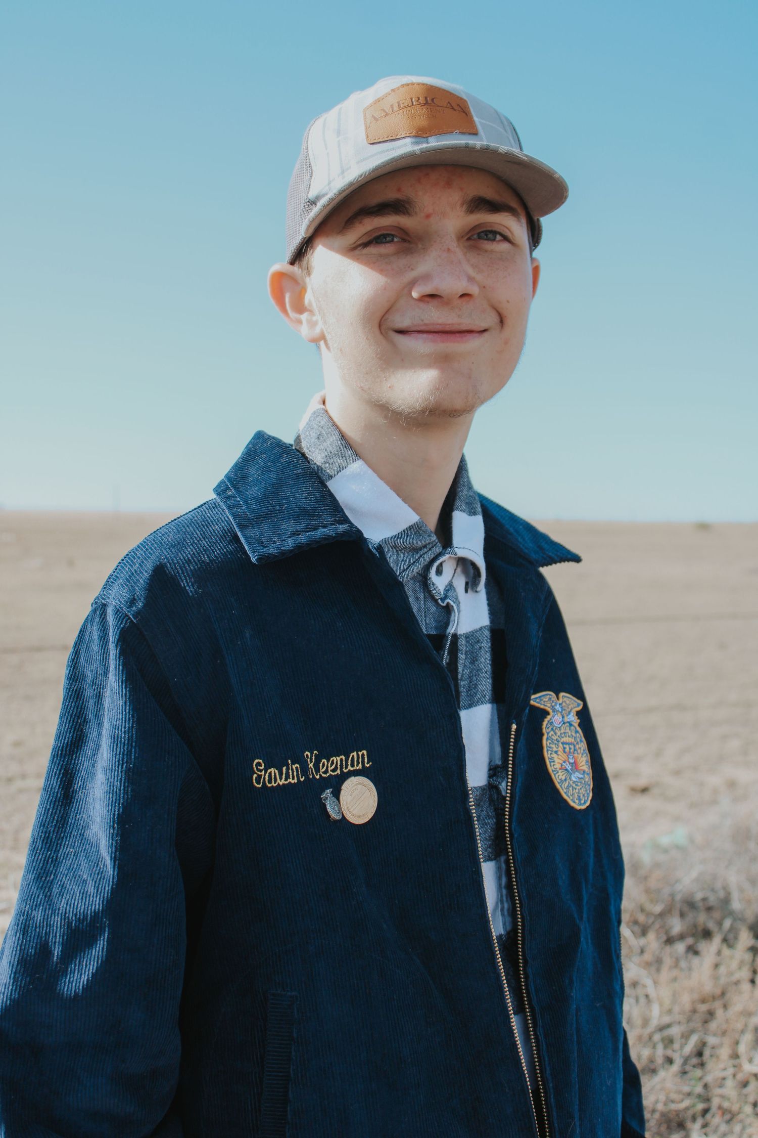 Young person in denim jacket and baseball cap smiles warmly against rural outdoor backdrop in multiple poses.