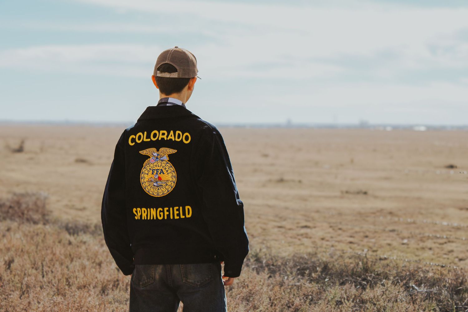 A black t-shirt with Colorado text stands against a desert landscape backdrop.