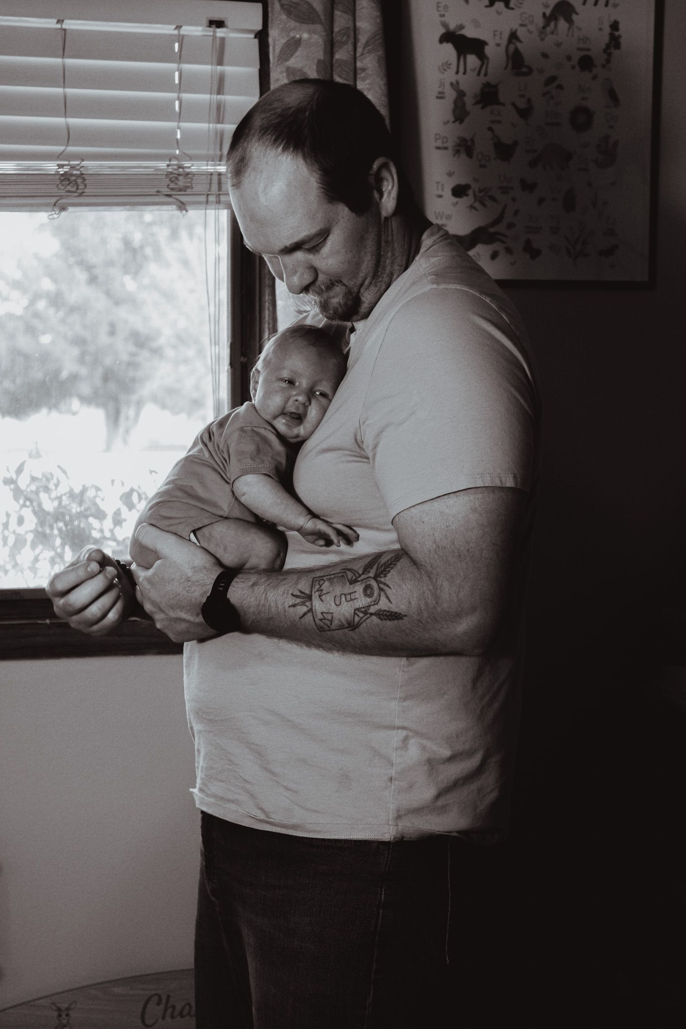 A touching black and white portrait of tender care and bonding between a parent and newborn by a window.