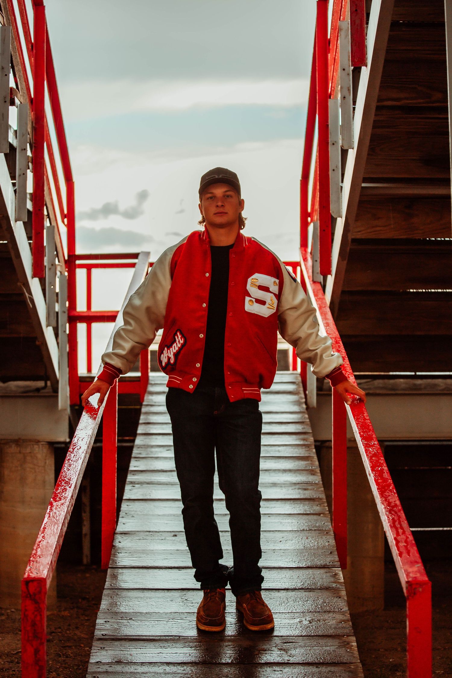 Red and white stadium steps create dramatic perspective with figure in varsity jacket.