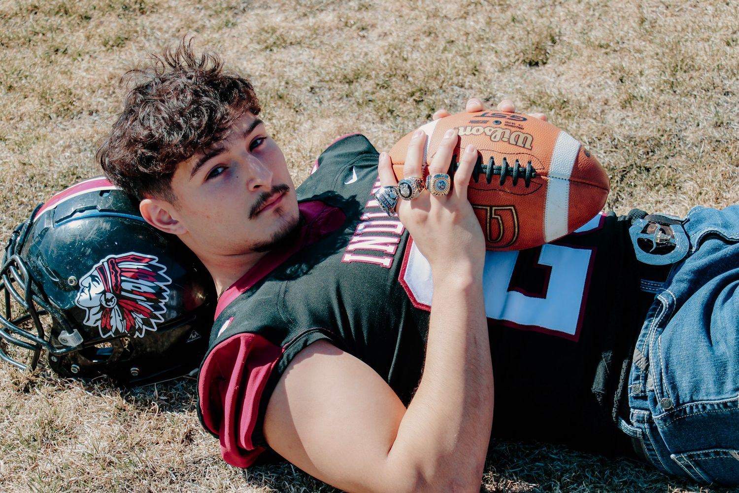 A person lying on grass taking a drink from a water bottle during a break from outdoor activities.