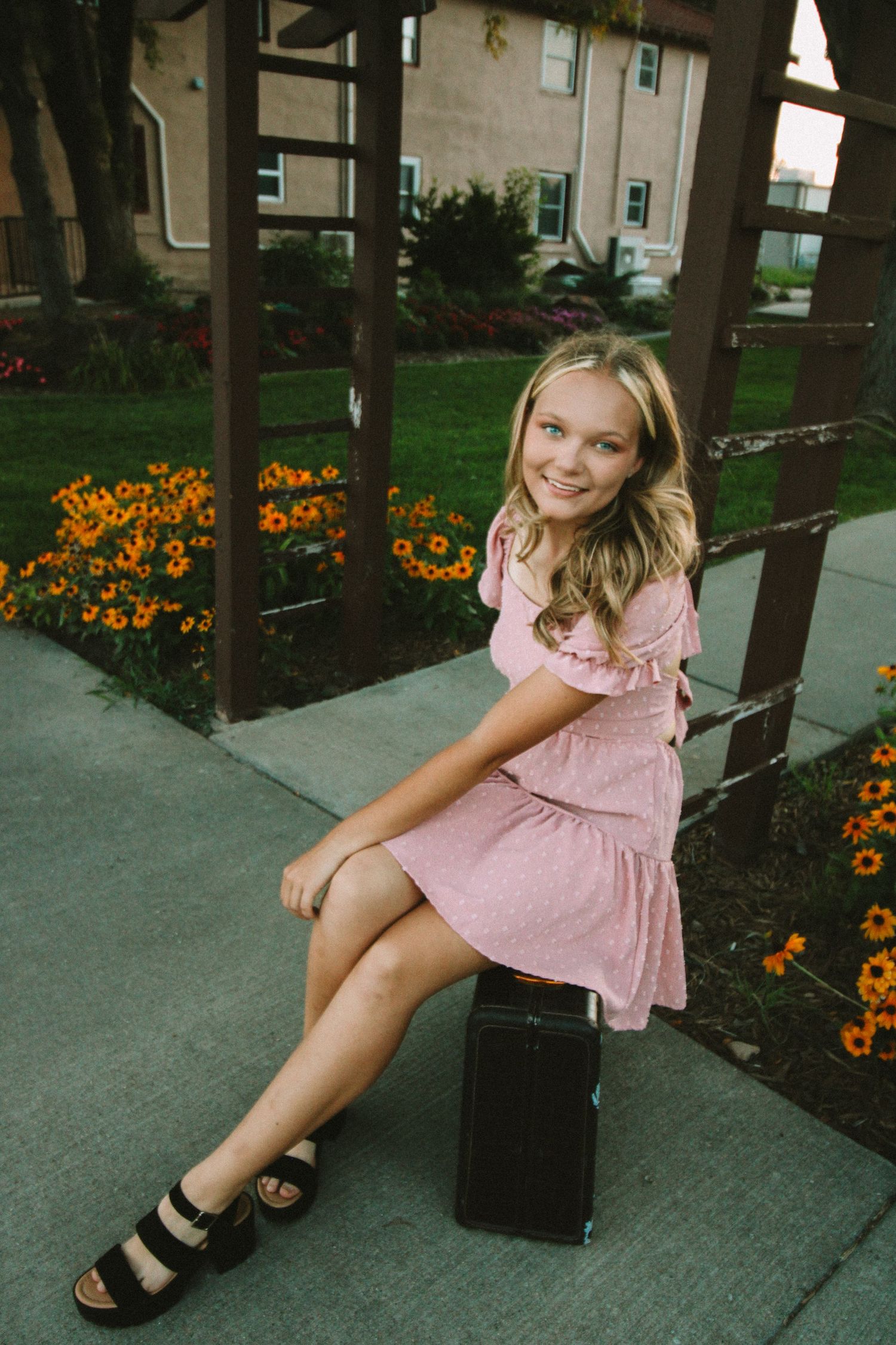 A series of photos showing a person in a pink dress sitting on a sidewalk near orange flowers and trees.