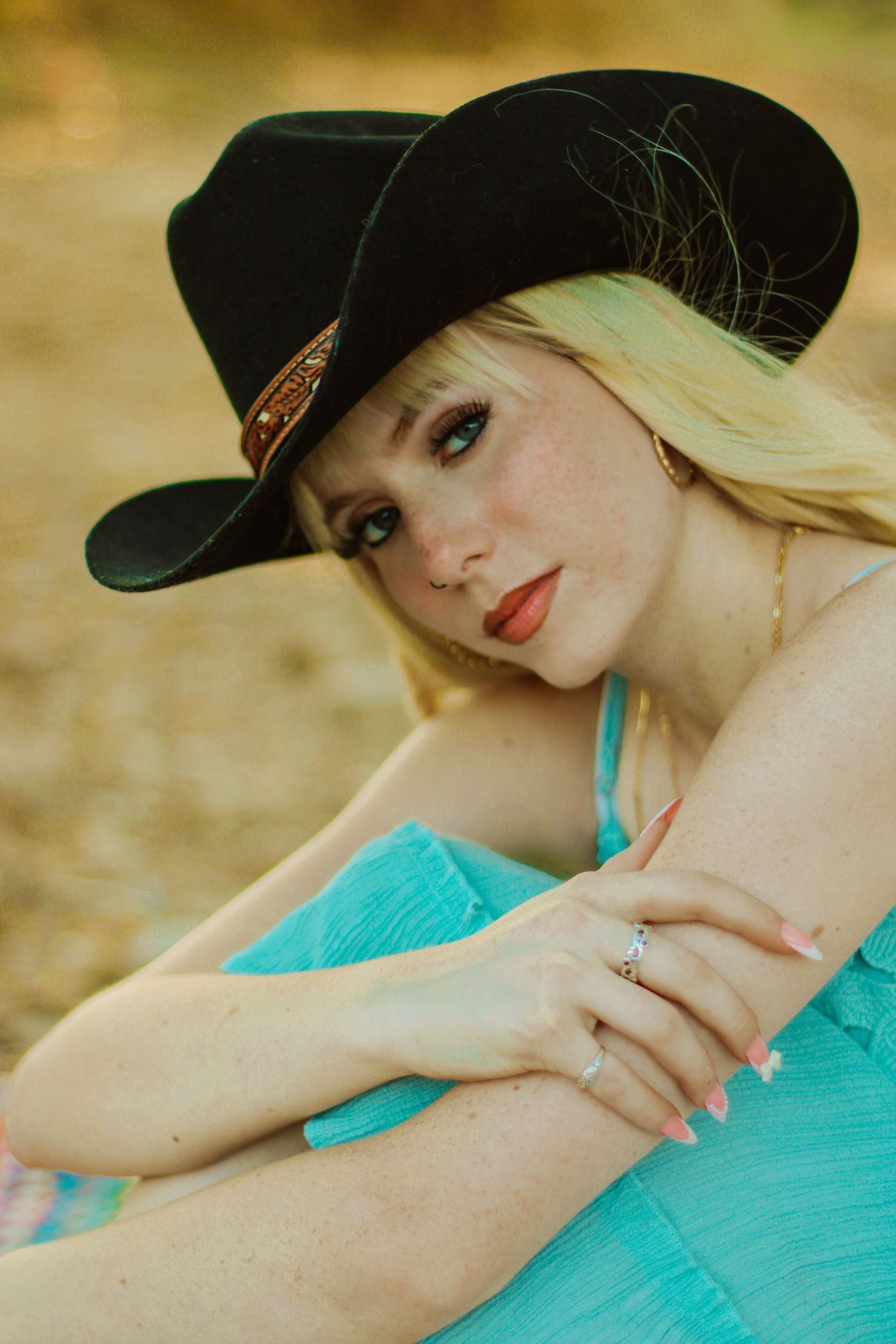 A series of artistic portraits showing someone in a black hat and turquoise top against a warm outdoor background.