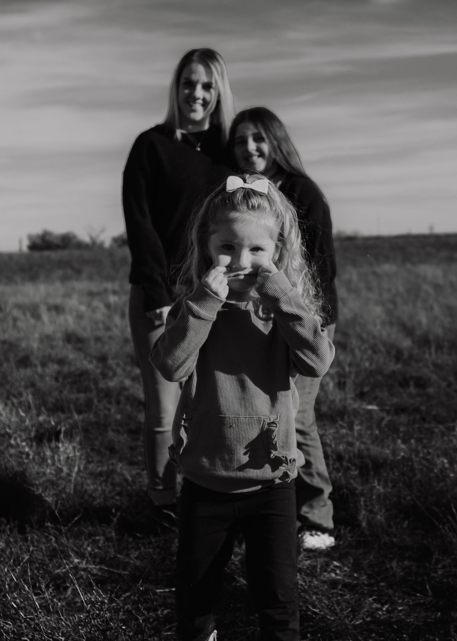 Black and white family portrait with a playful young child in the foreground.