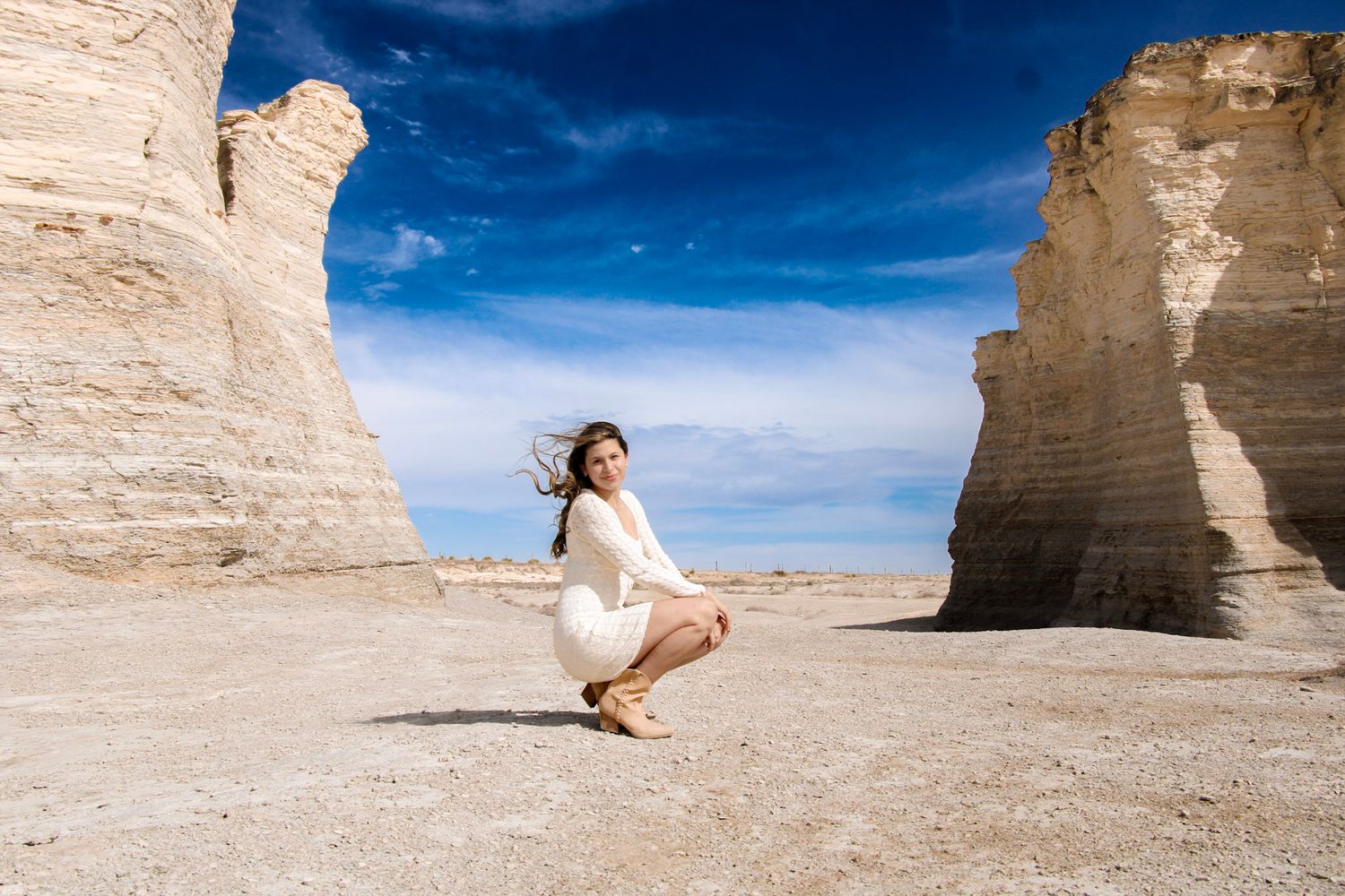 A person in a white dress stands gracefully among towering limestone formations in Monument Rocks, Kansas.