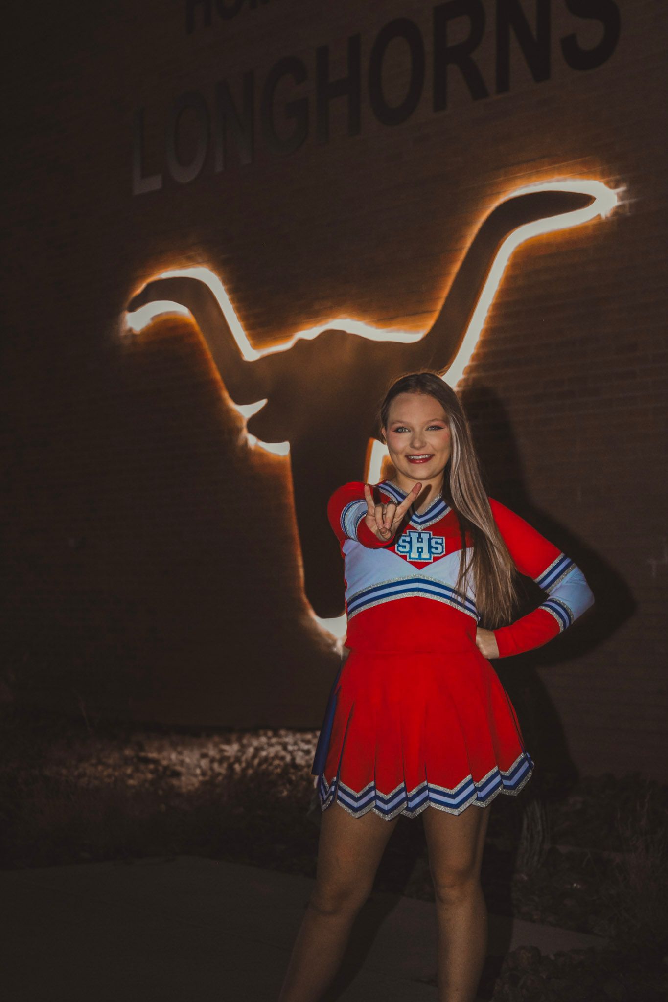 Cheerleader in red and white uniform performs light painting photography tricks with glowing trails at night.
