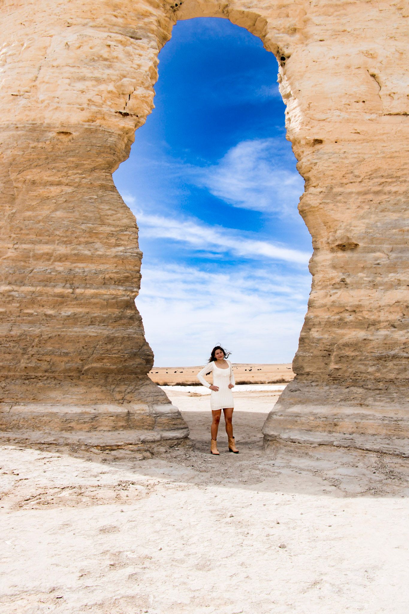 A sequence of white limestone cave openings framing the bright blue desert sky against sandstone rock formations.