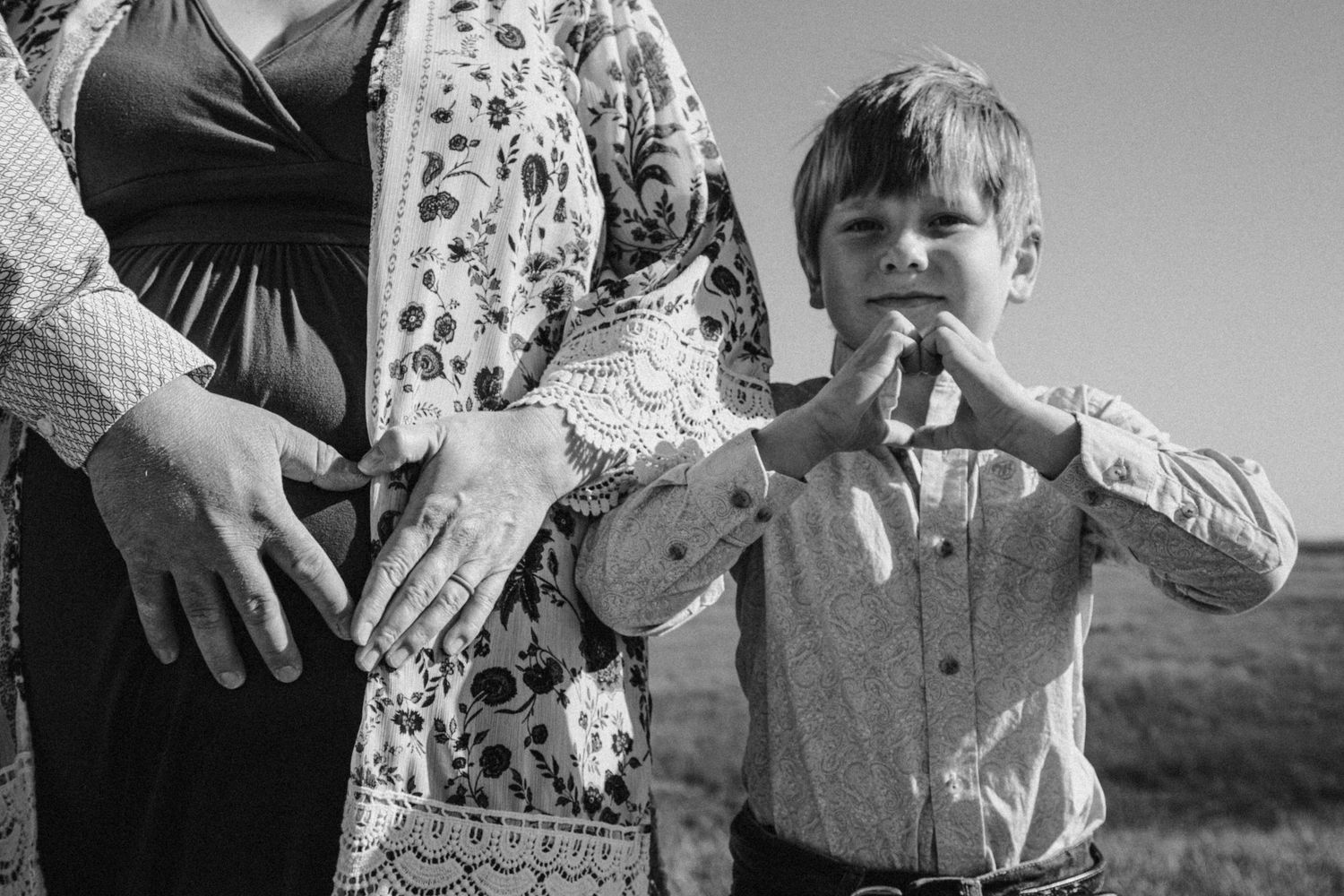Vintage black and white photograph showing a child in dress clothes standing next to an adult in a floral dress.