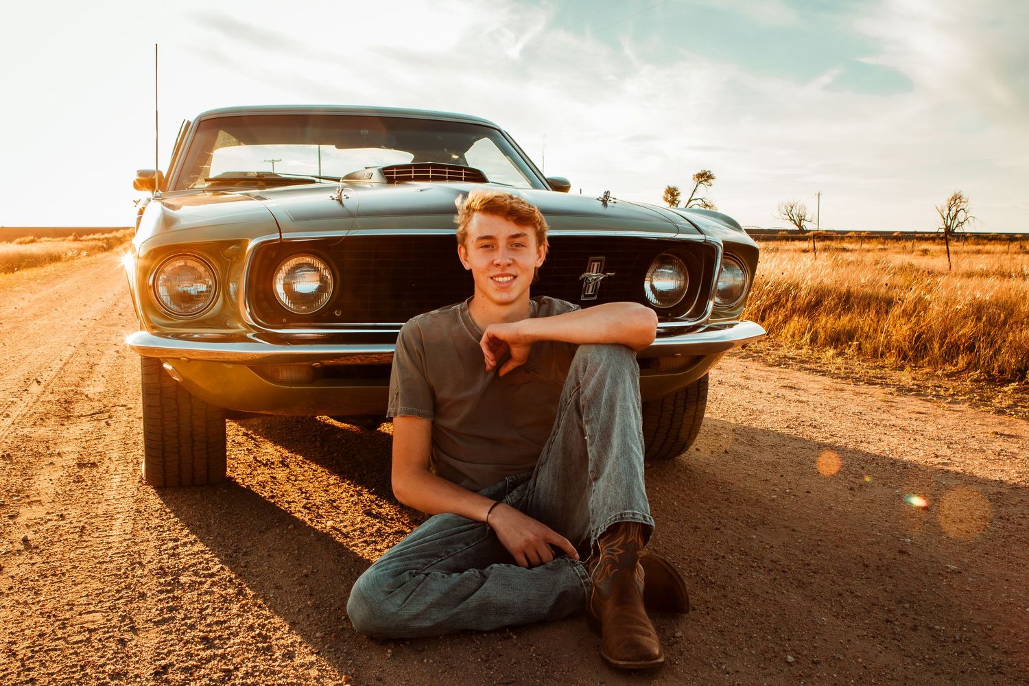 A vintage car parked in a golden field at sunset creates a nostalgic rural scene.