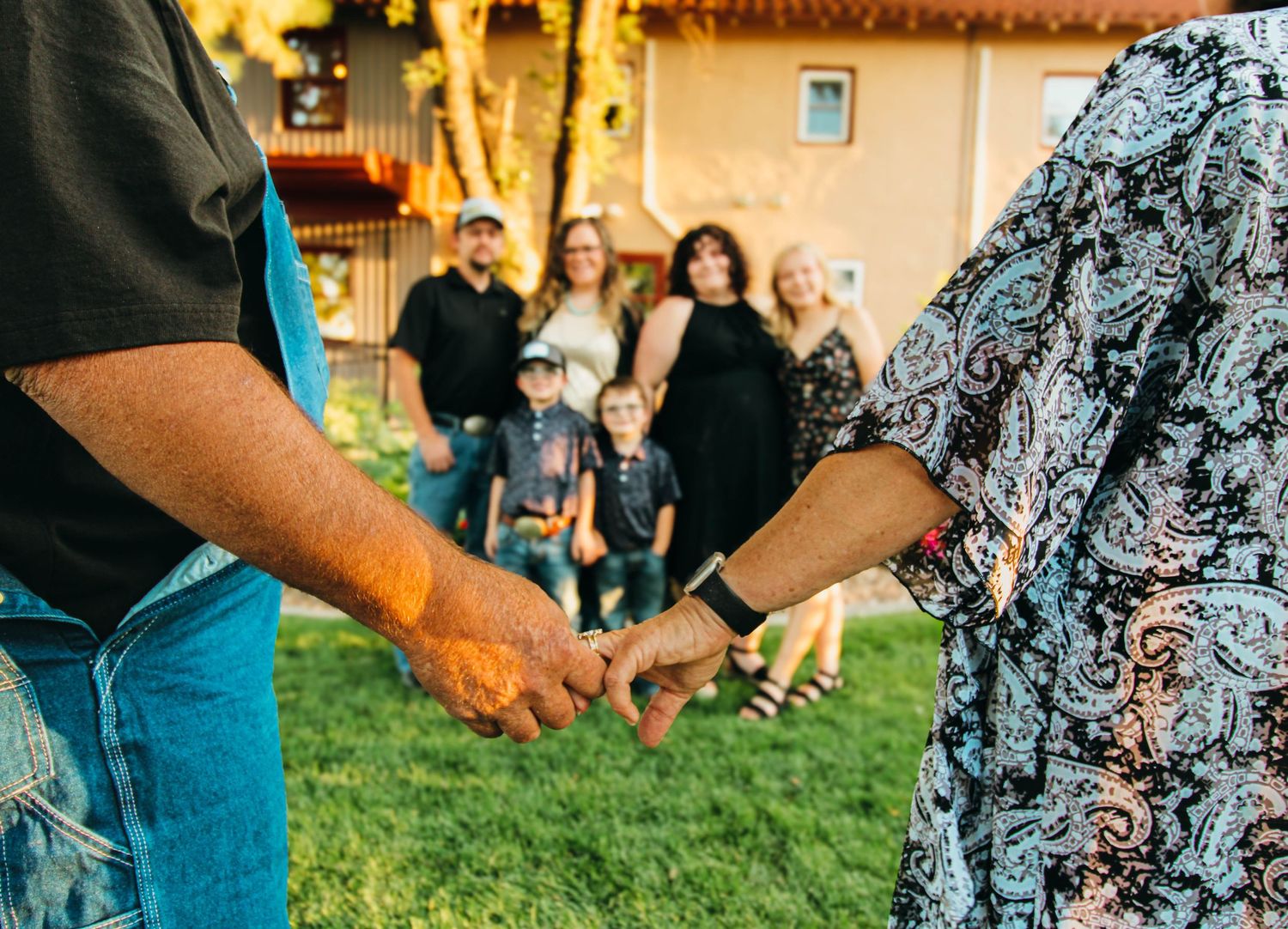 A close-up shot of hands holding during an outdoor family gathering.