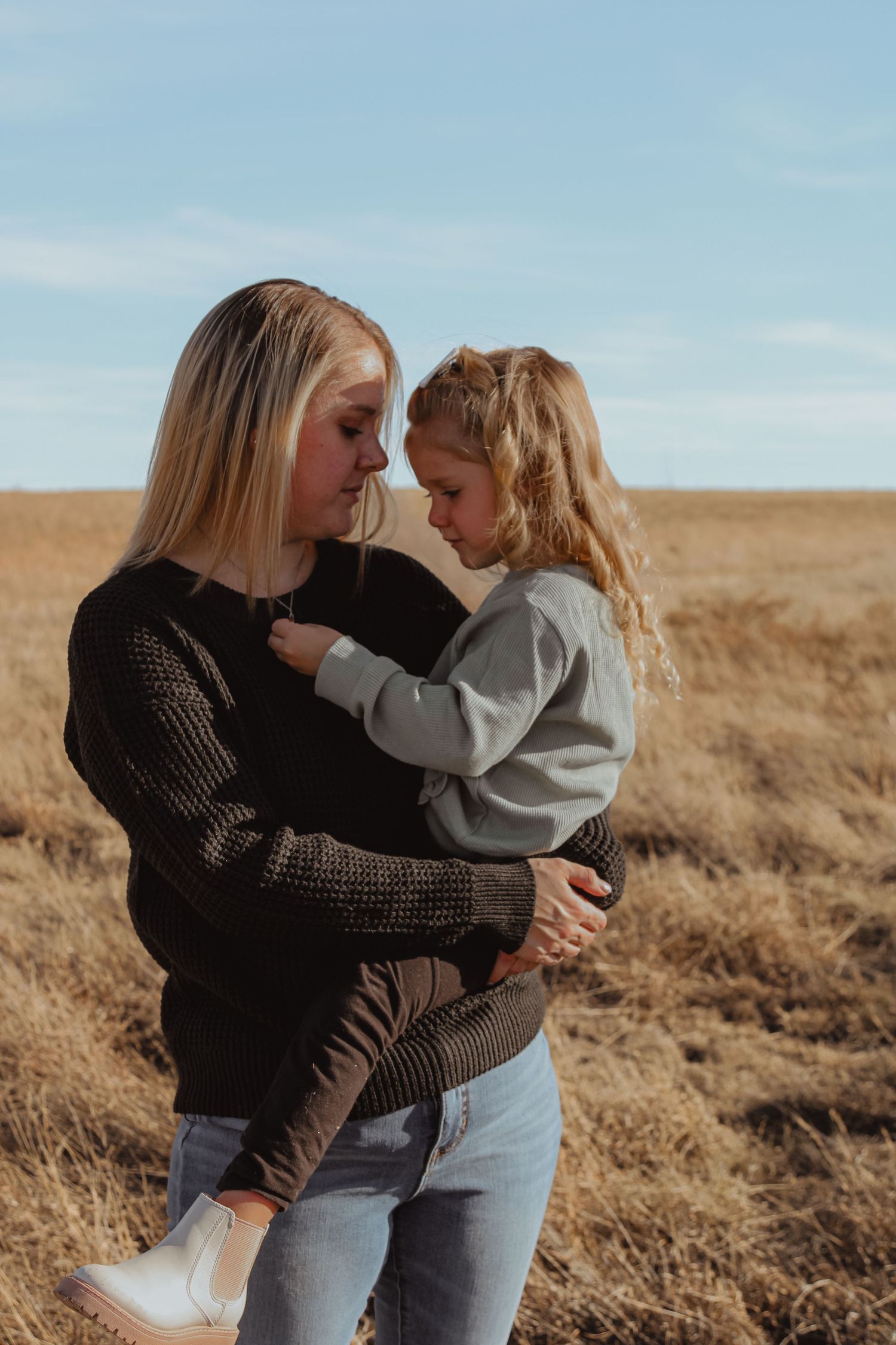 Tender moment between parent and child against a golden prairie backdrop.