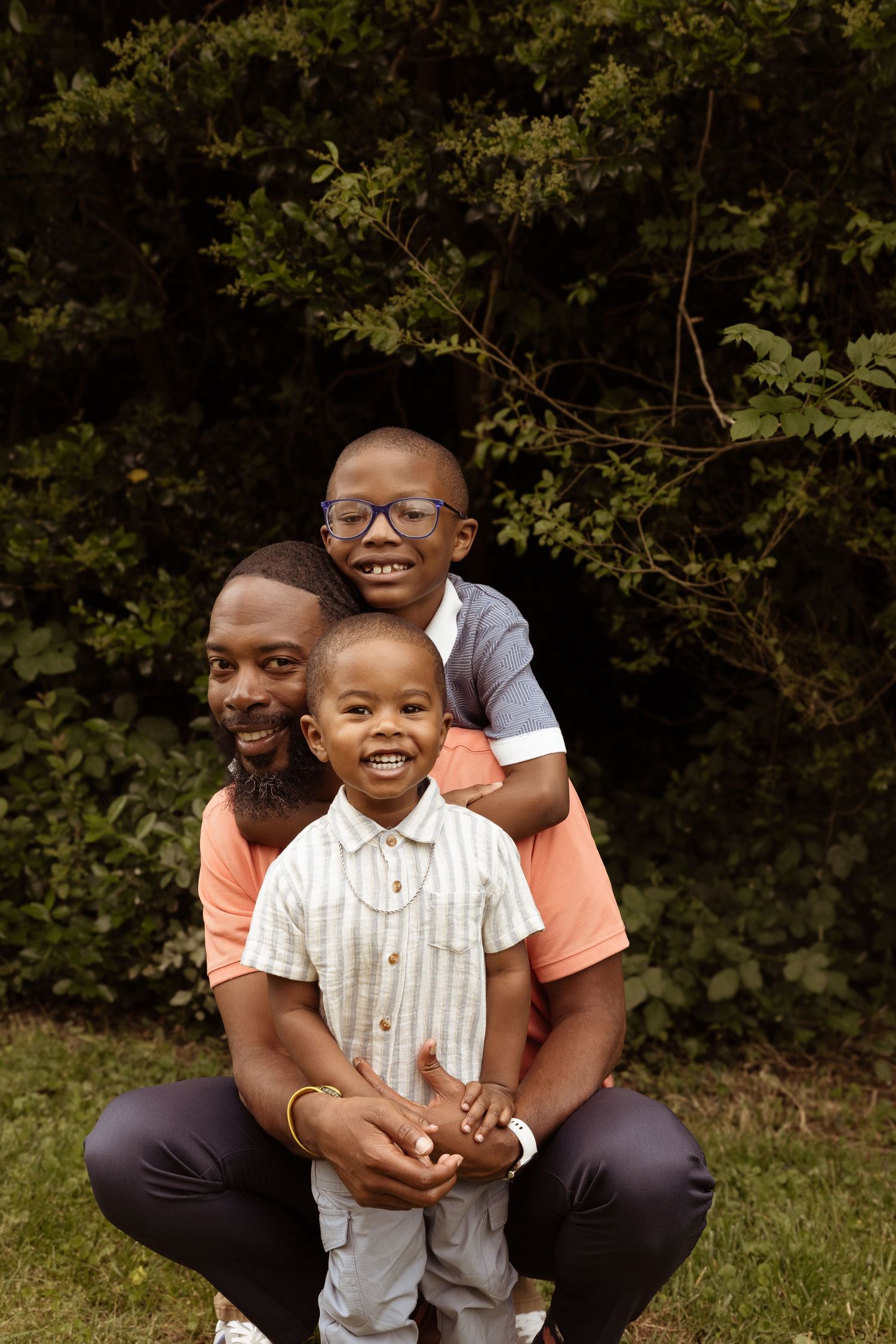 Family portrait of father and two children smiling together outdoors.
