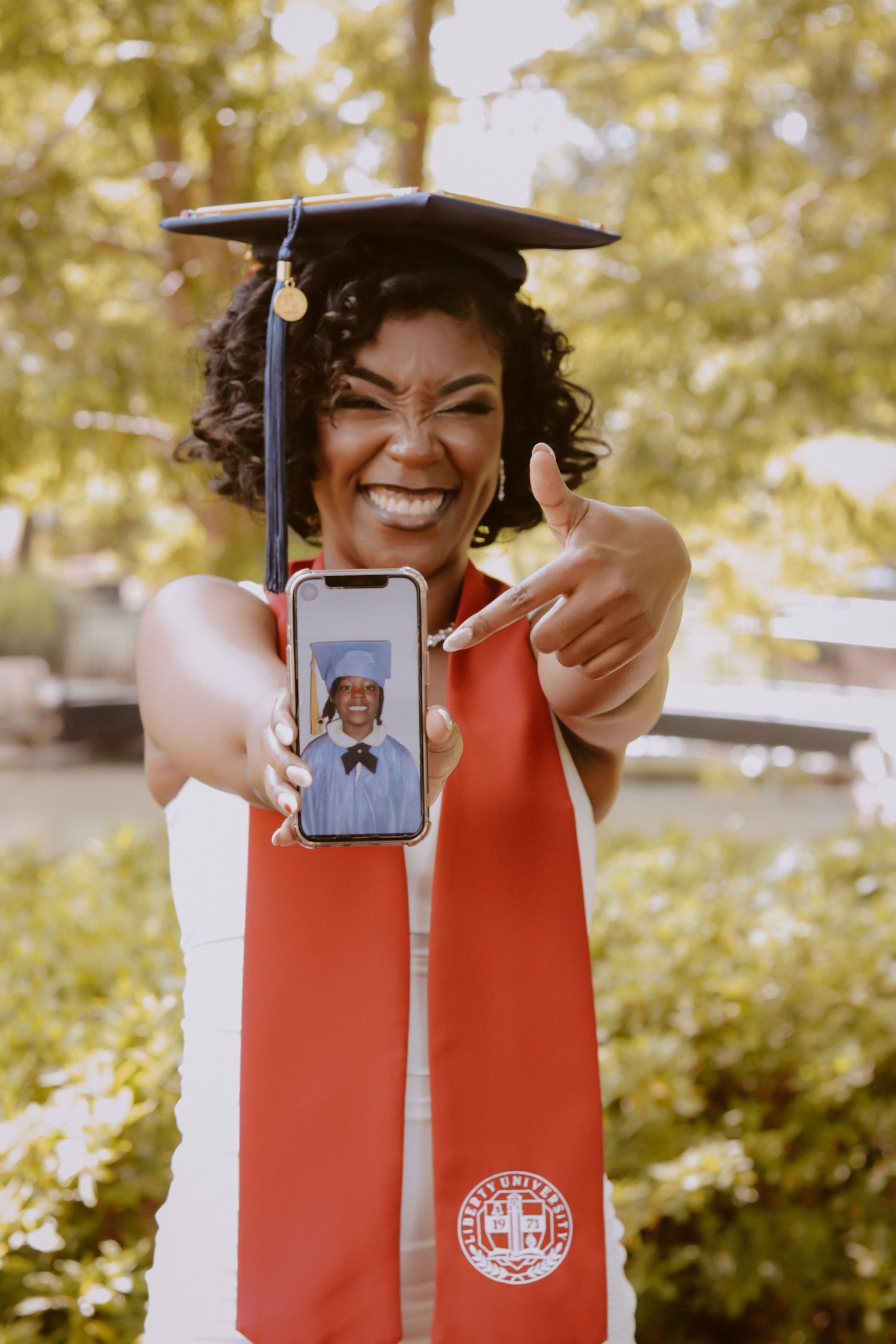 Creative graduation photo series showing miniature graduate photo displayed in red diploma holder case.