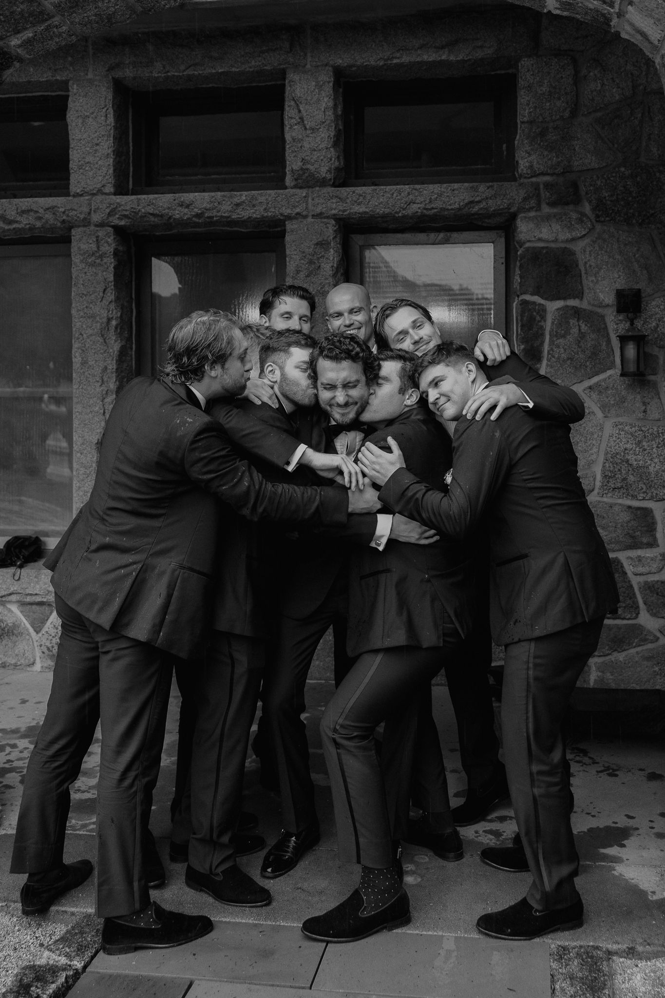 A sequence of black and white photos showing a group of men in suits playfully wrestling and horsing around.