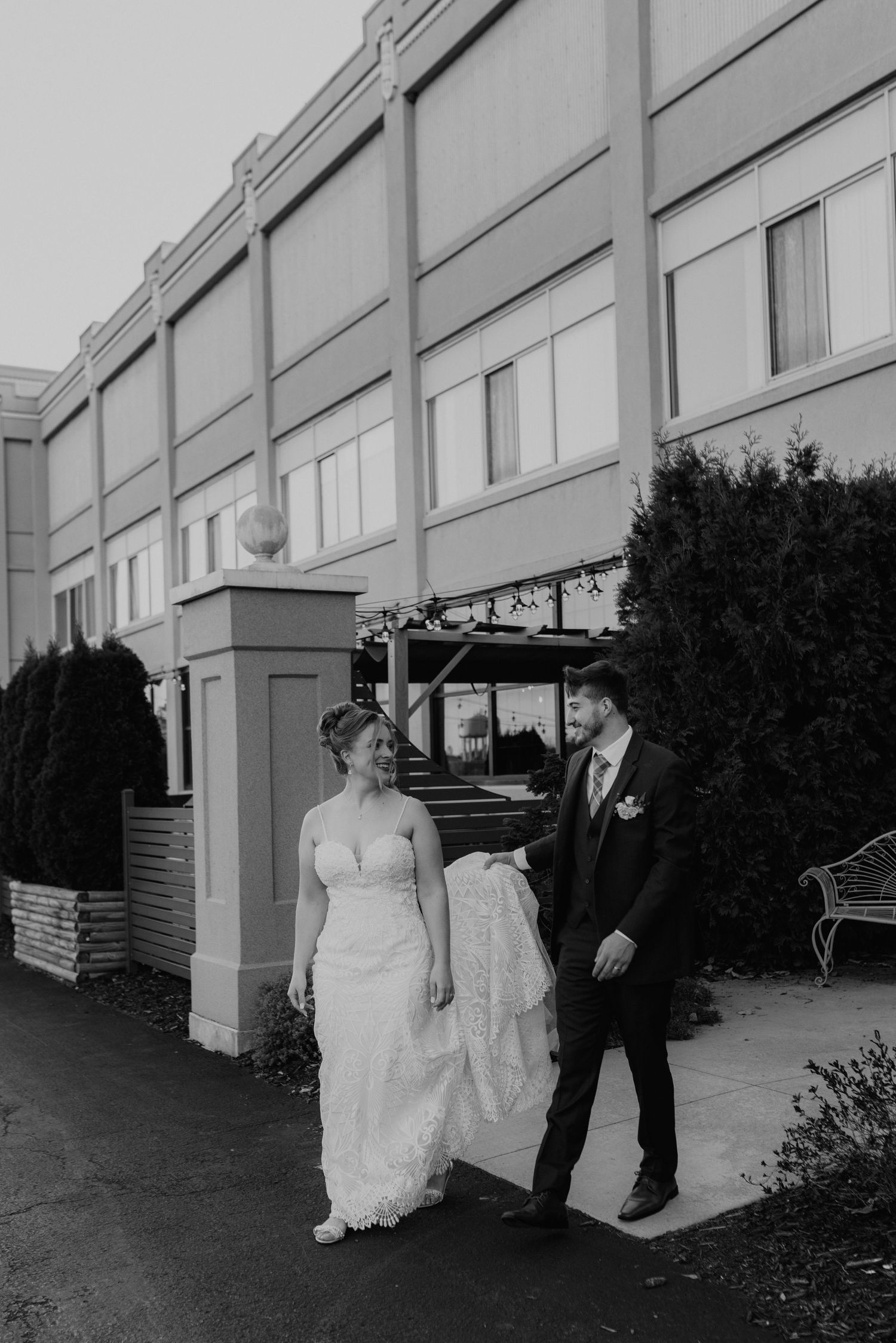 A couple poses outside an elegant building on their wedding day with classic architecture in the background.